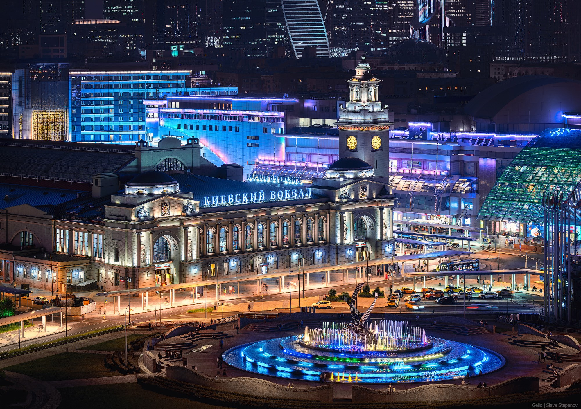 Historical building of the Kiyevsky railway station in Moscow with architectural illumination. Illuminated fountain on the Square of Europe. Aerial view, urban photography, Gelio.