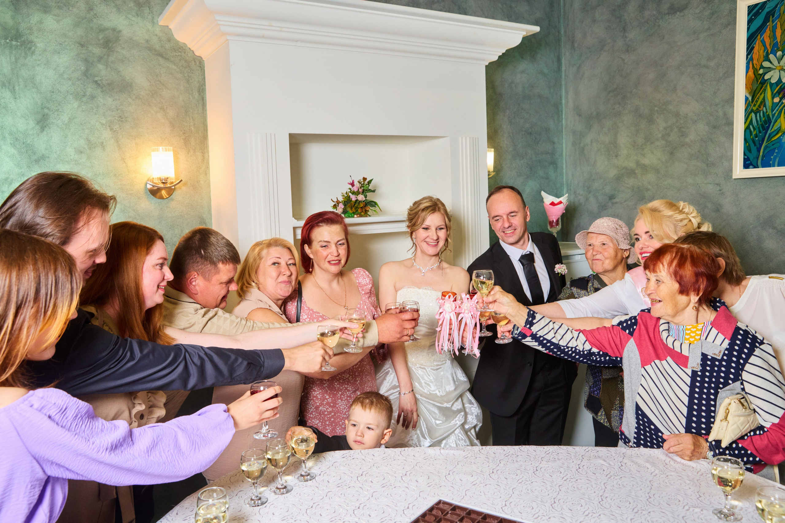 Гости и молодожёны поднимают бокалы в фуршетном зале