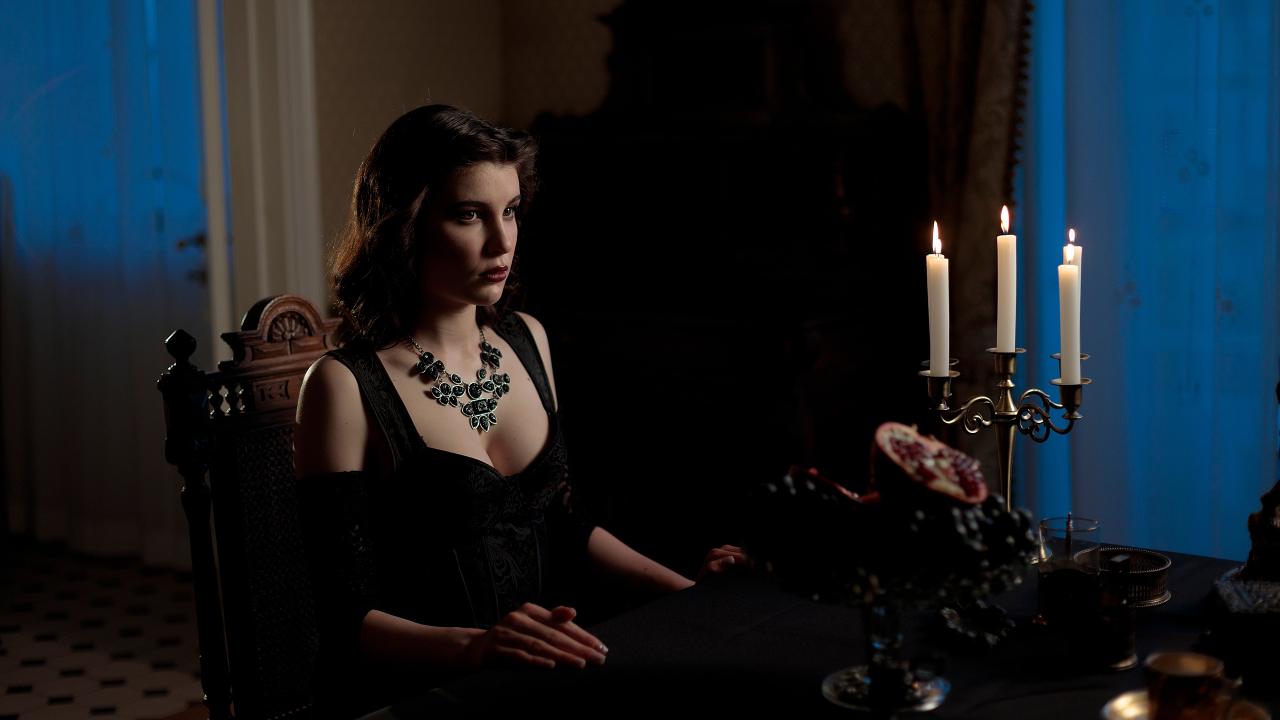 Девушка сидит за столом, за окном синий час, задний план окрашен в синий цвет