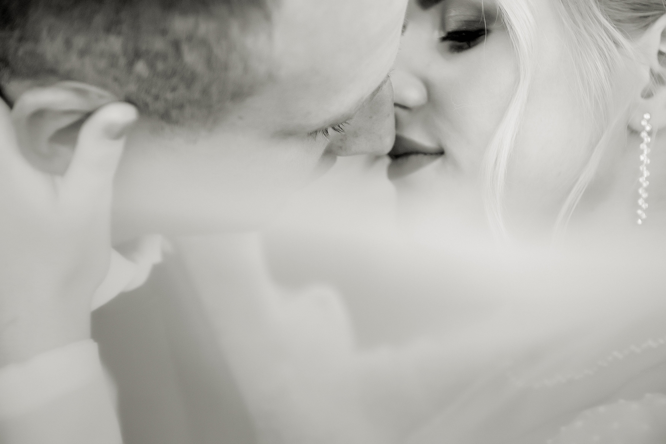 Чёрно-белая фотография свадебной пары, нежно целующейся друг с другом.
