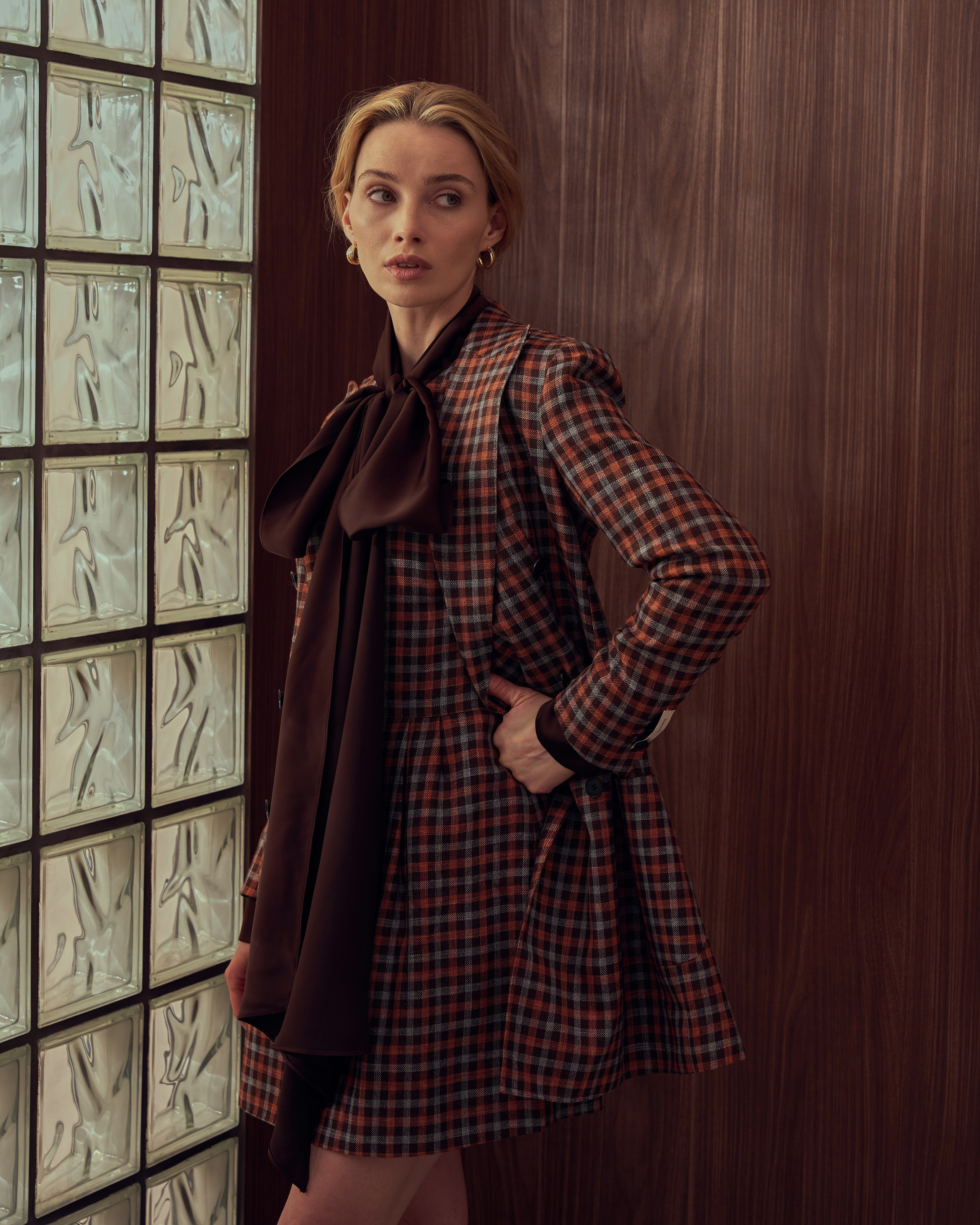 Съемка одежды, девушка с бантом, в гольфах, в коричневом костюме стоит у окна