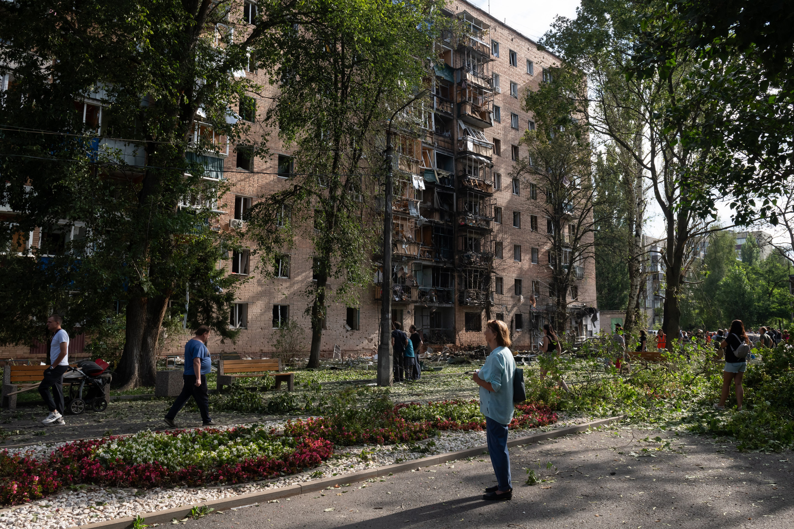 People gather at an apartment building damaged after shelling by the Ukrainian side in Kursk, Russia, Sunday, Aug. 11, 2024.