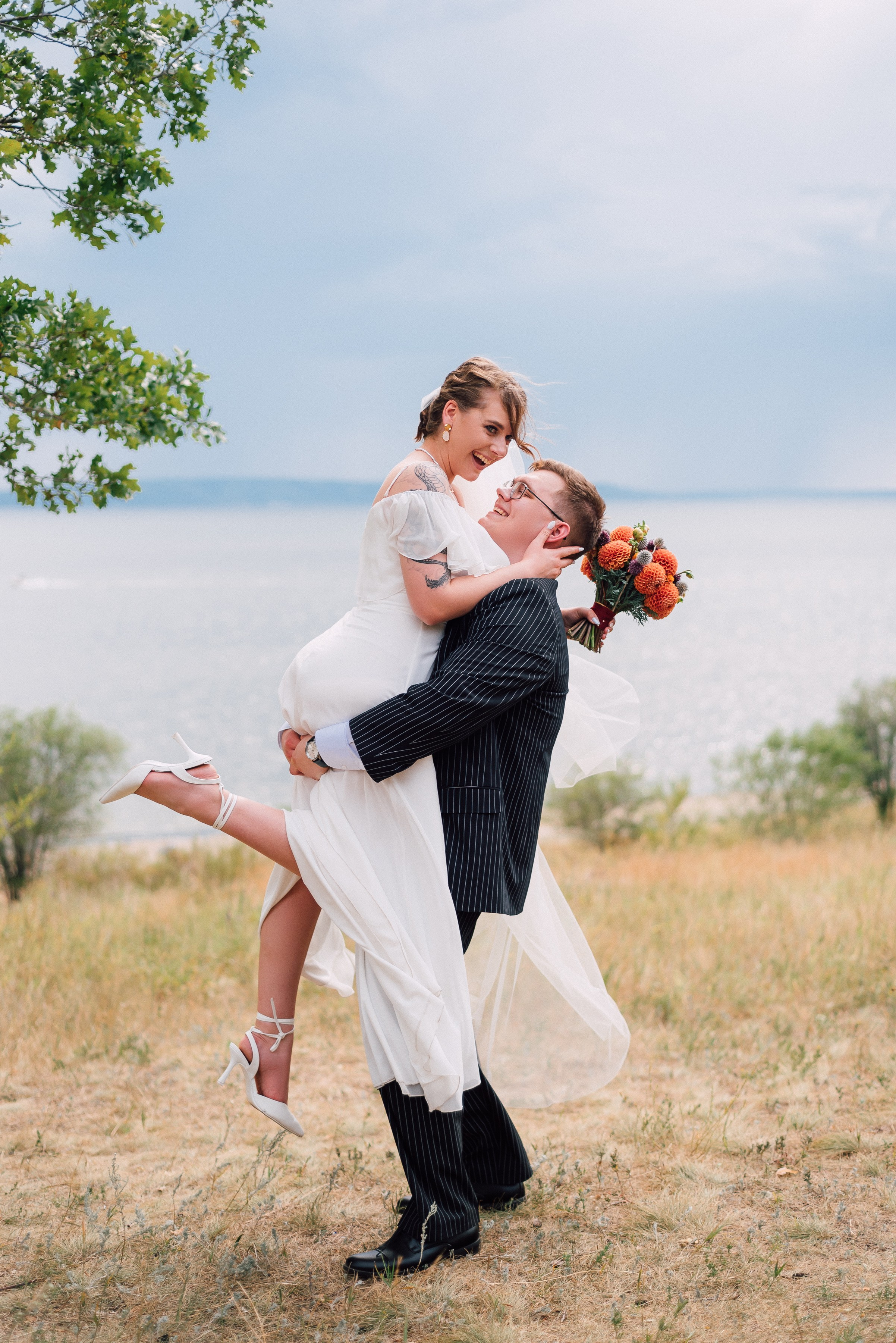 Жених держит невесту на руках на фоне Волги