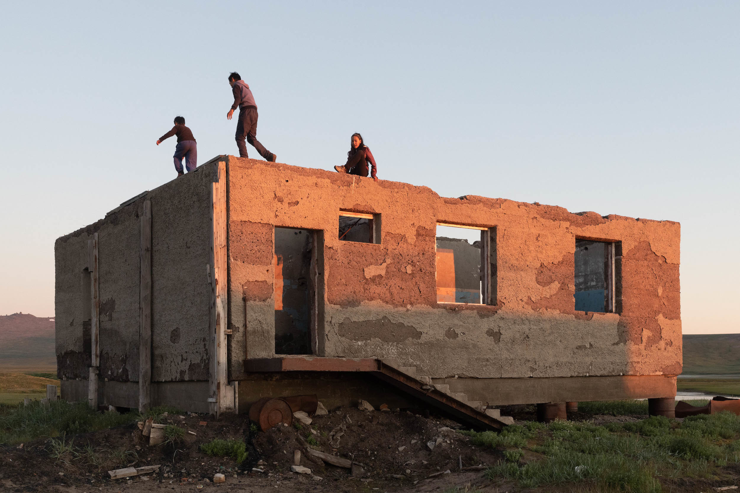 Летний закат за полярным круг почти бесконечен, он плавно переходит в рассвет. Подростки играют в руинах.