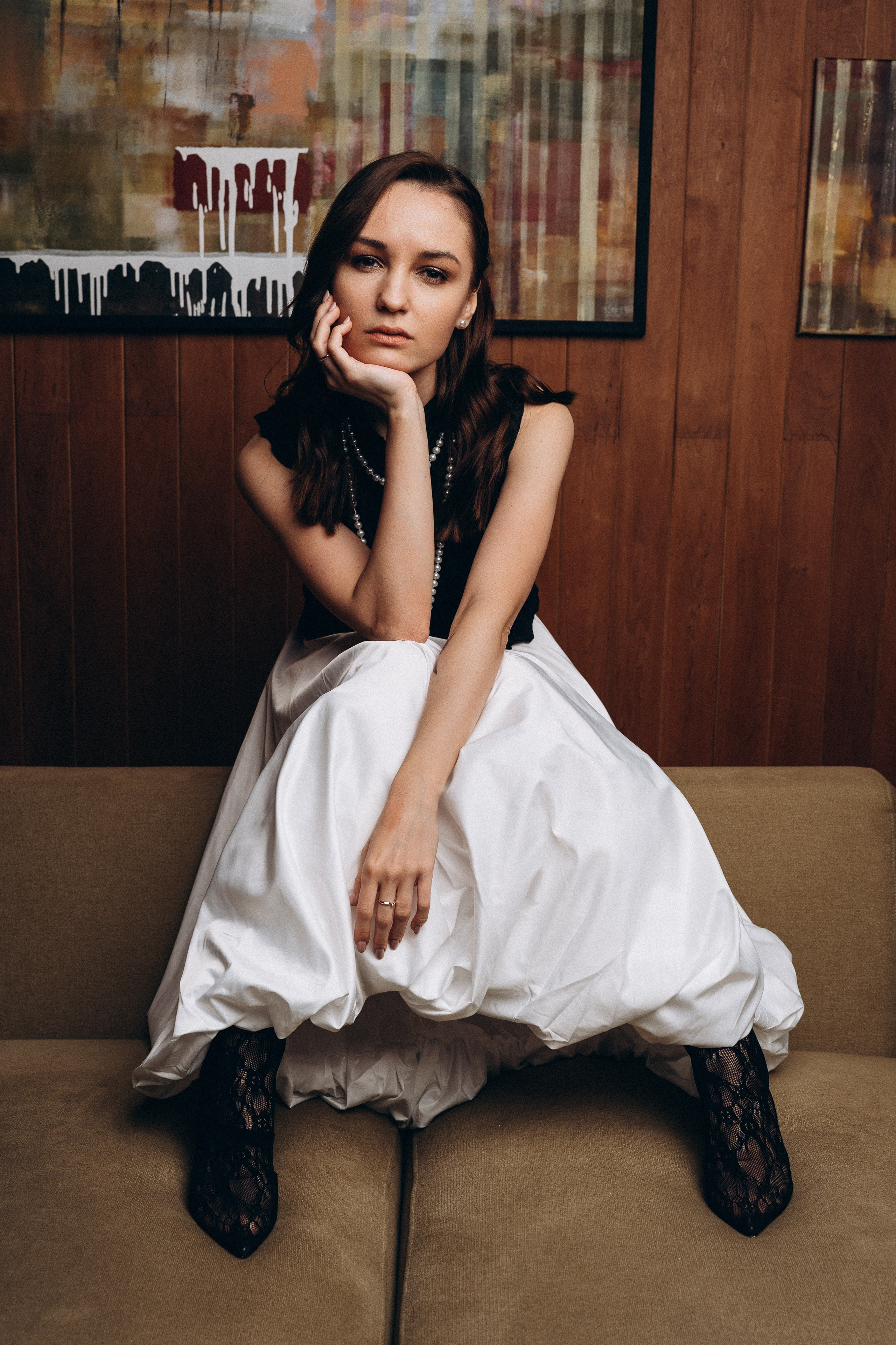 портрет девушки в юбке баллон которая грустит сидя на спинке дивана