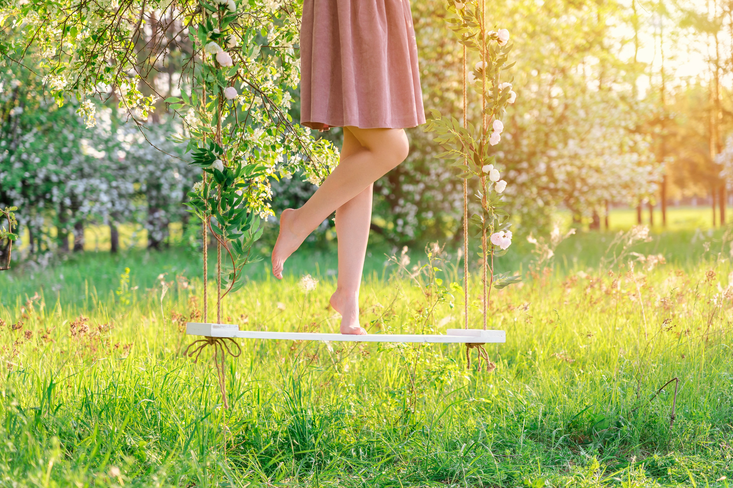 Ноги девушки на качелях, фотосессия на природе в яблоневом саду