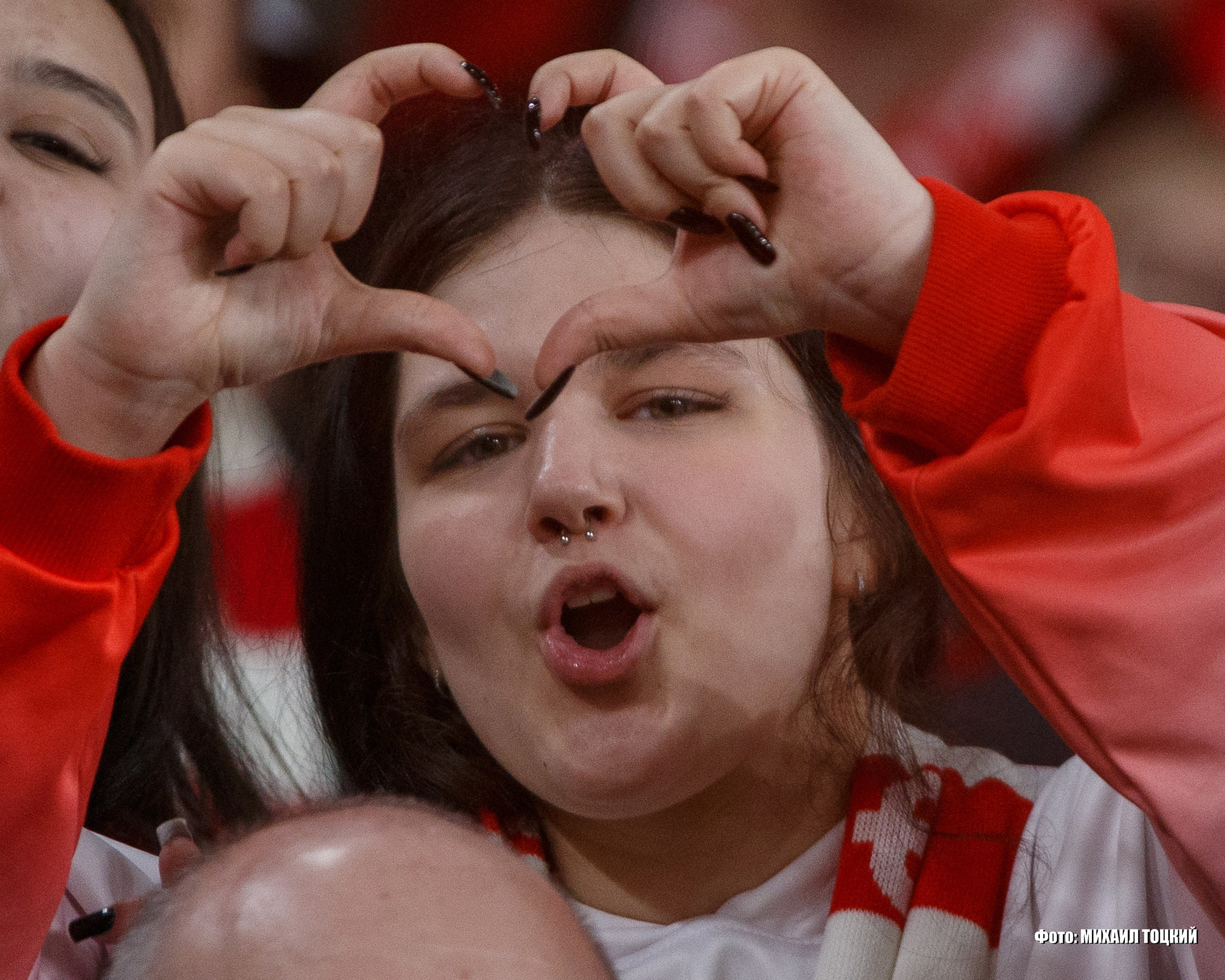 Красивая болельщица Спартака на трибуне Лукойл Арены показывает жест сердечко
