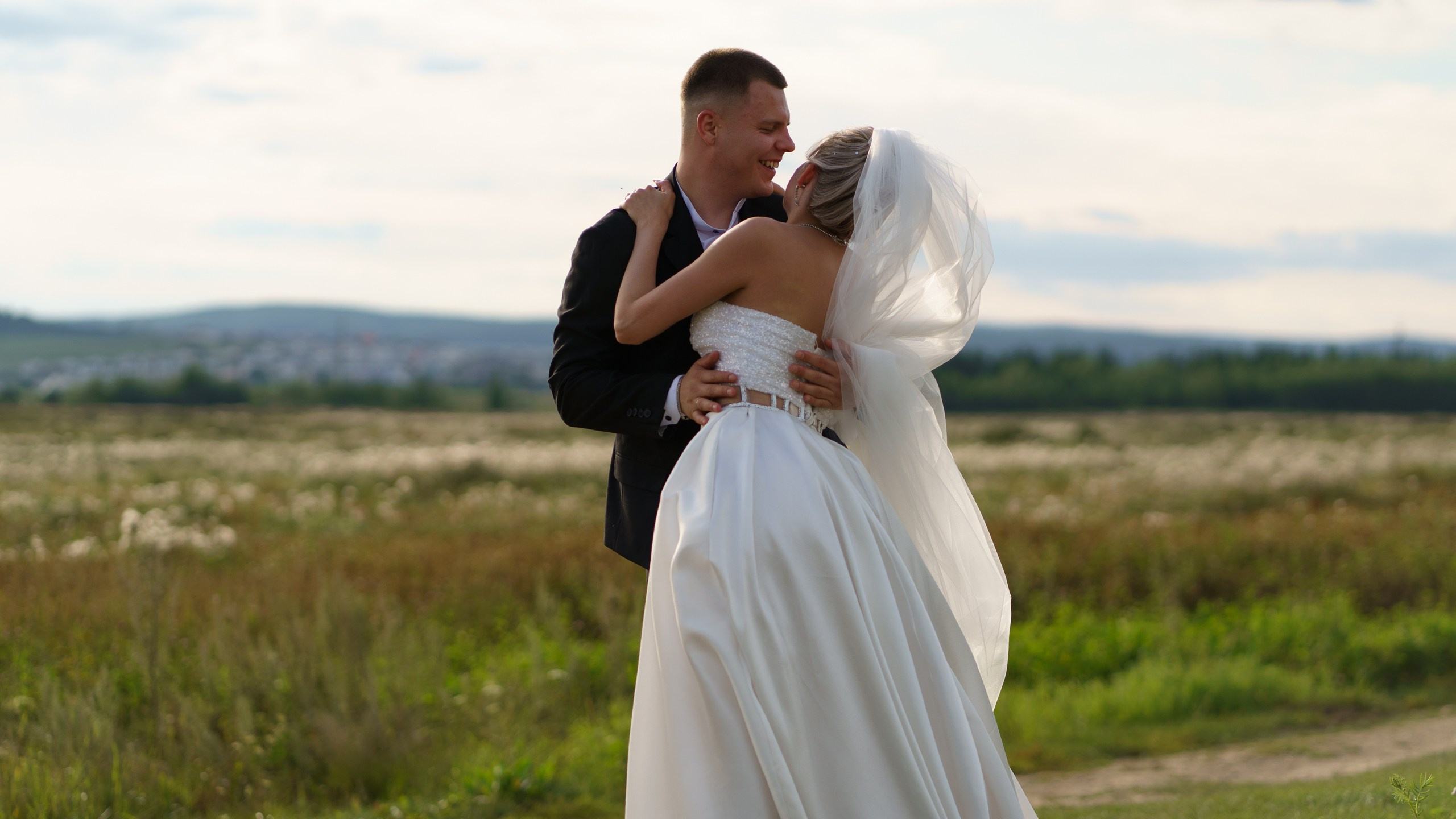 Любовь, запечатлённая в кадре: жених нежно держит невесту, а её фата, подхваченная лёгким ветерком, придаёт сцене особую романтичность. В их взглядах — целый мир чувств | свадебная фотосессия в уникальных локациях Екатеринбург