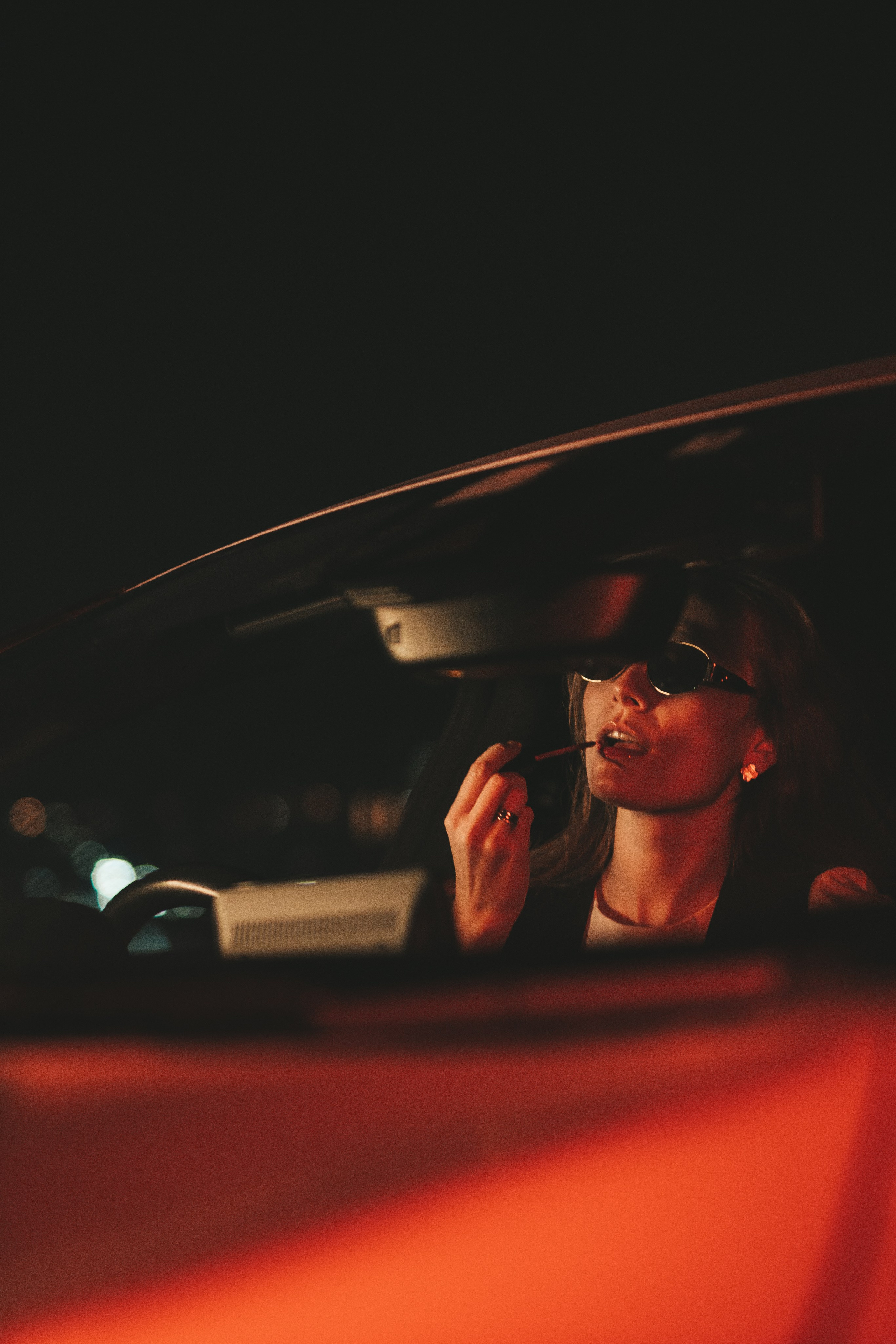 девушка внутри машины красит губы, кадр снаружи