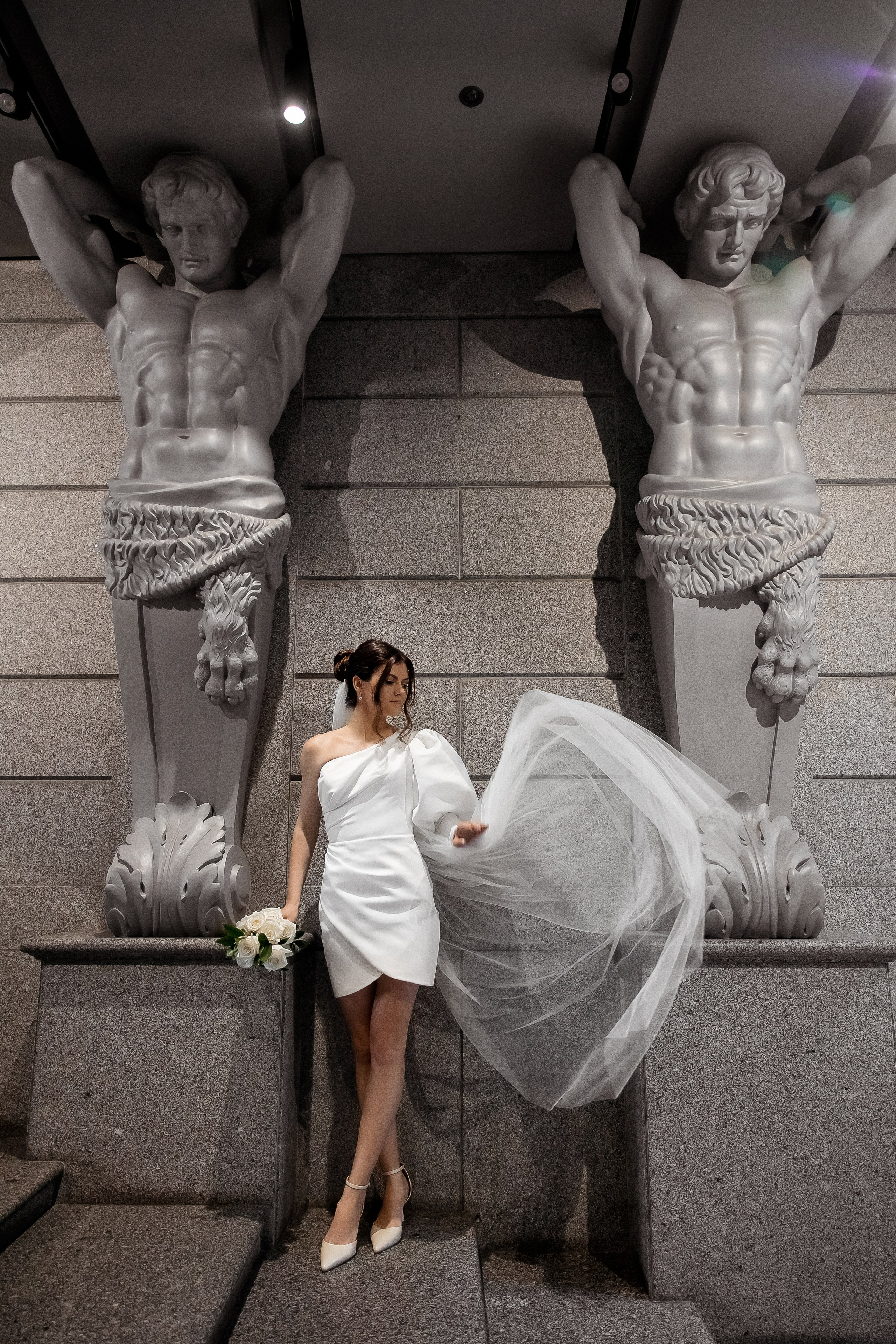 Летящая фото красивой невесты около Атлантов в отеле Гамма