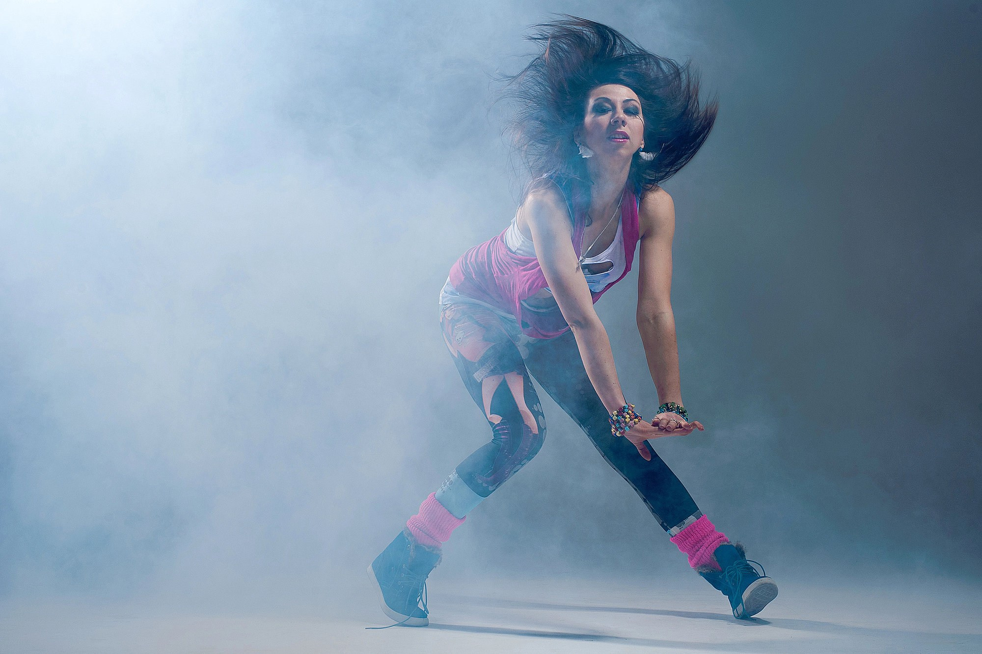 Танцовщица в тумане выполняет низкую динамичную посадку, создавая эффект силуэта в рассеянном свете. Танцевальная съёмка в Москве и Истринском районе.