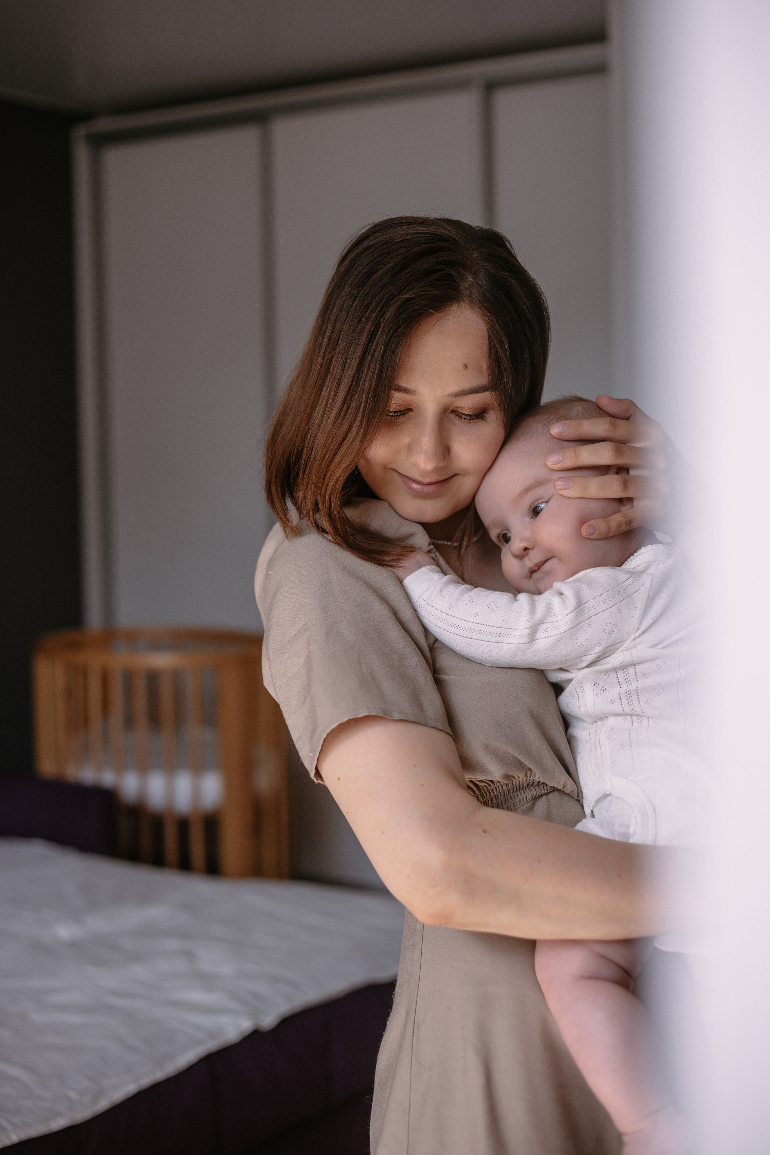 мама держит малыша на руках фотограф подглядывает за их жизнью