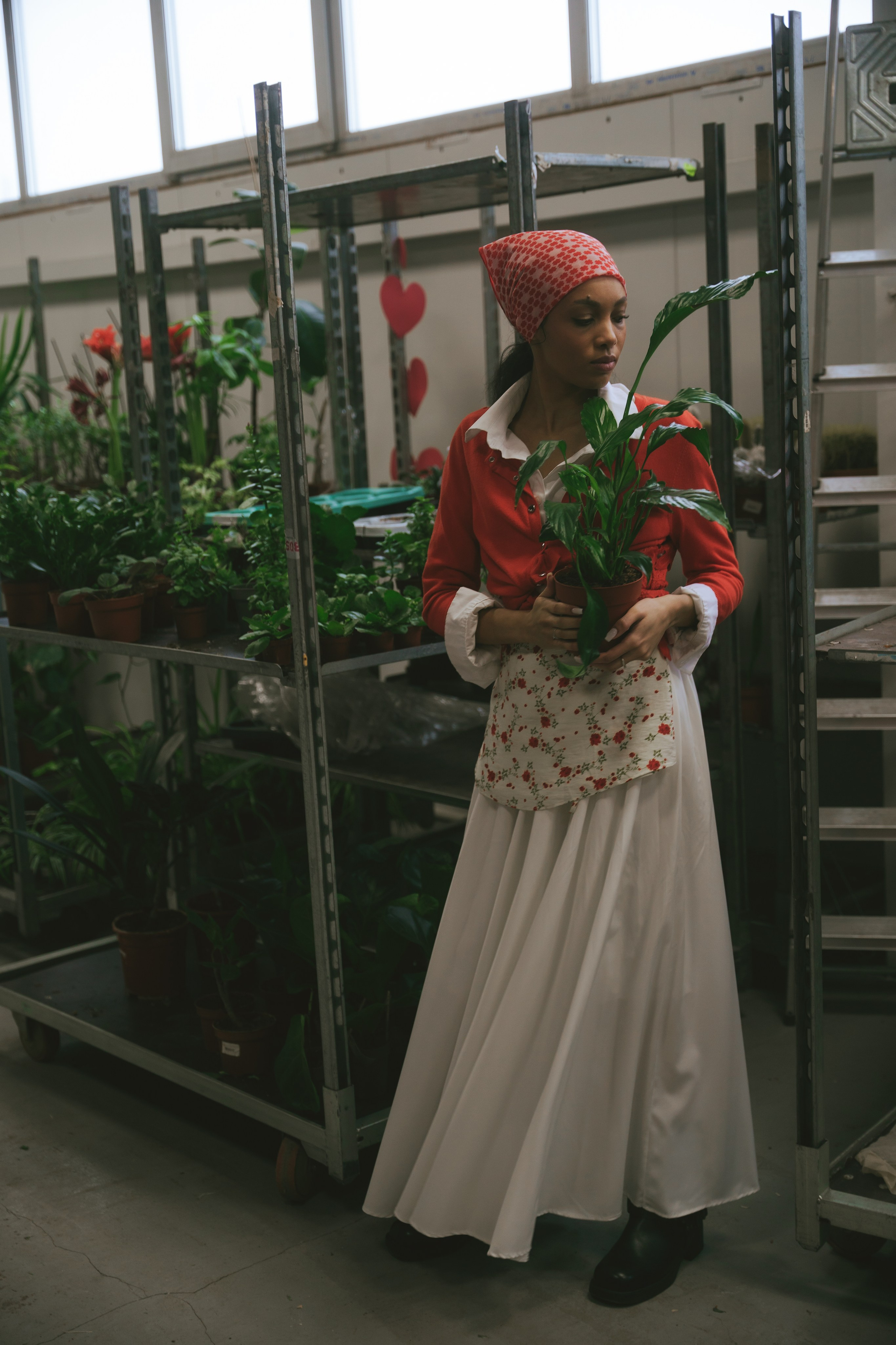 Женщина в стильном ретро-образе среди зелени цветочной базы