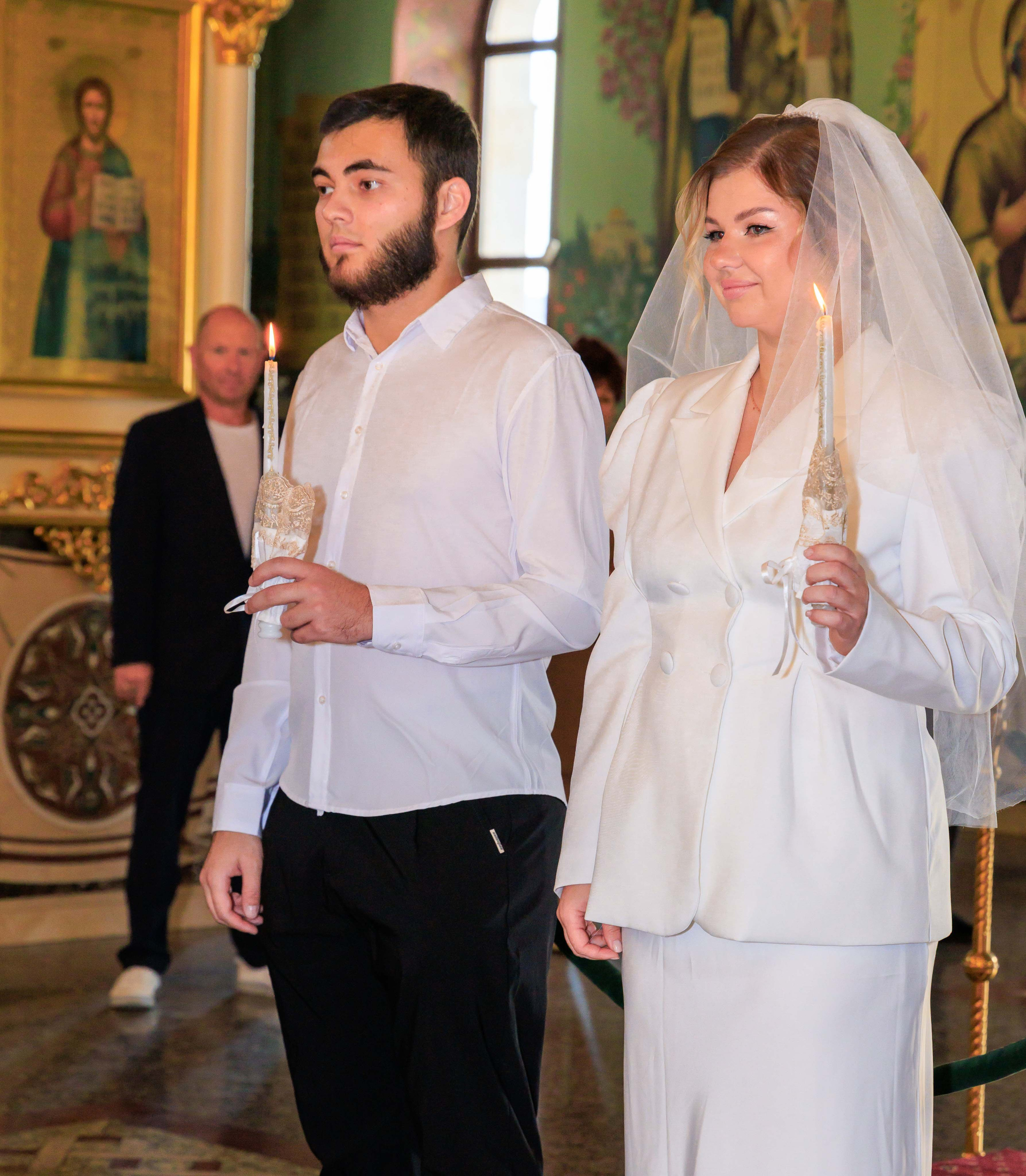 Жених и невеста держат в руках зажженные венчальные свечи.