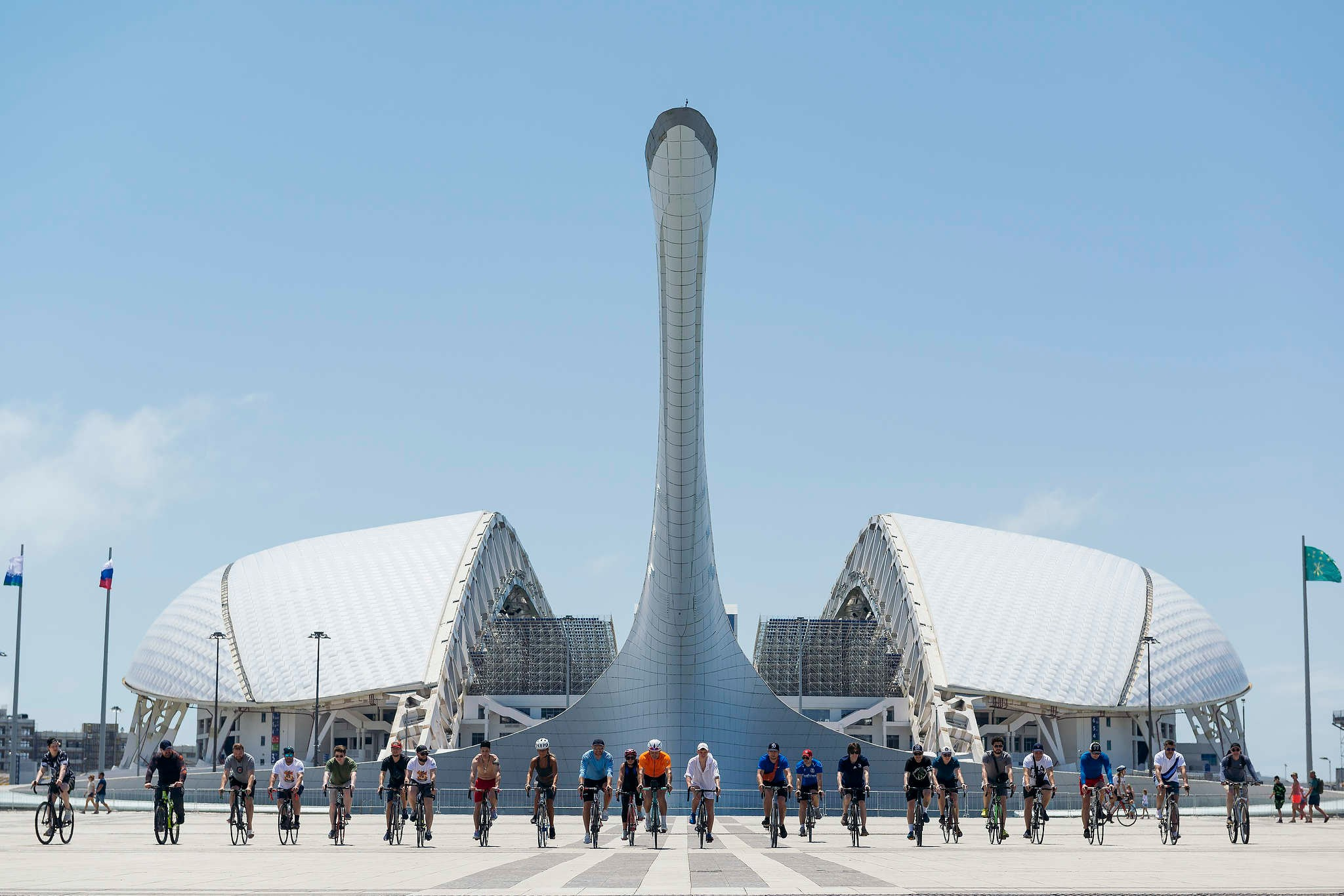 Любительская хоккейная команда катается на велосипедах на фоне стадиона Фишт в Олимпийском парке на сборах в городе Сочи. Съемка 2023 года.