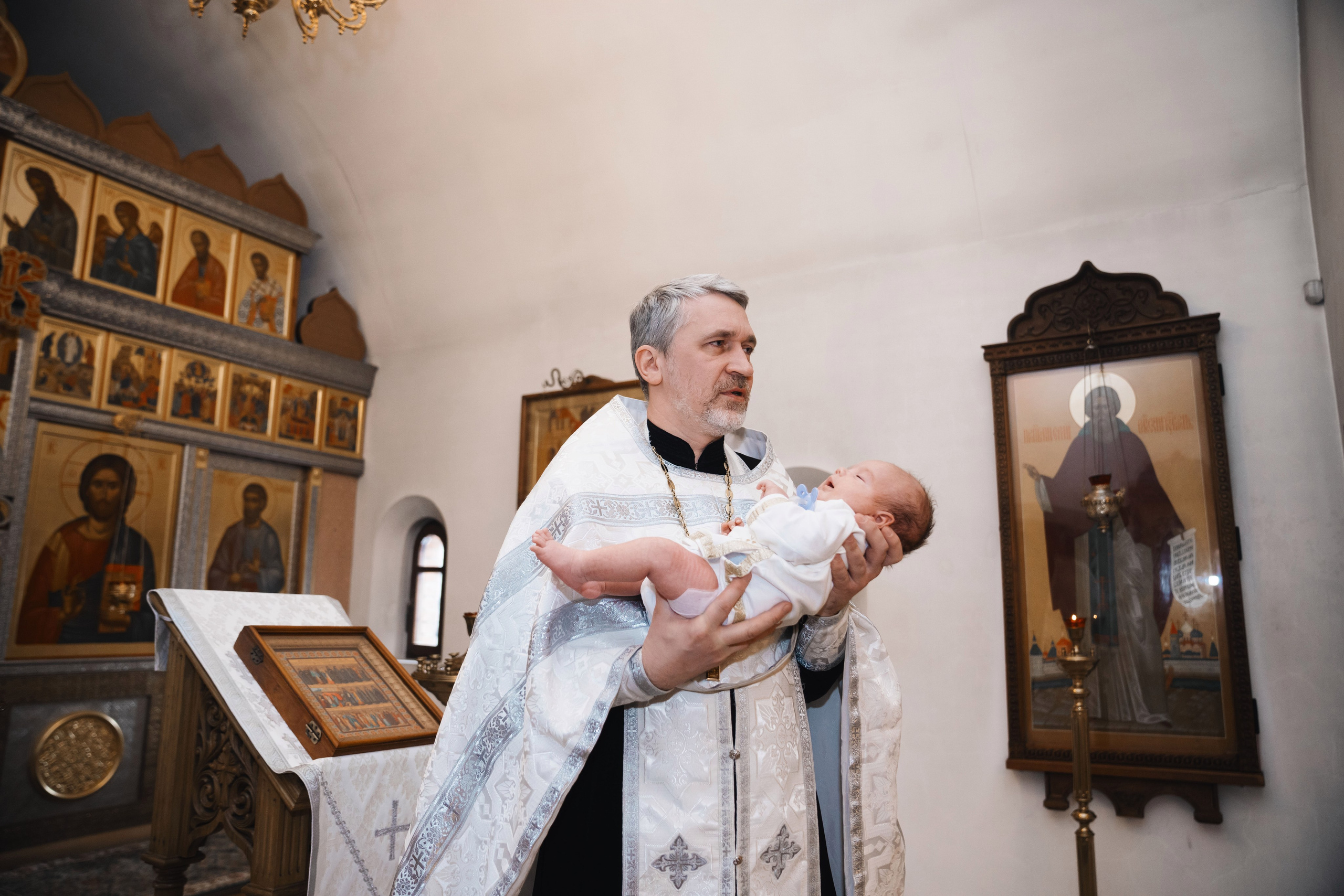 обряд воцерковления, священник держит младенца на руках