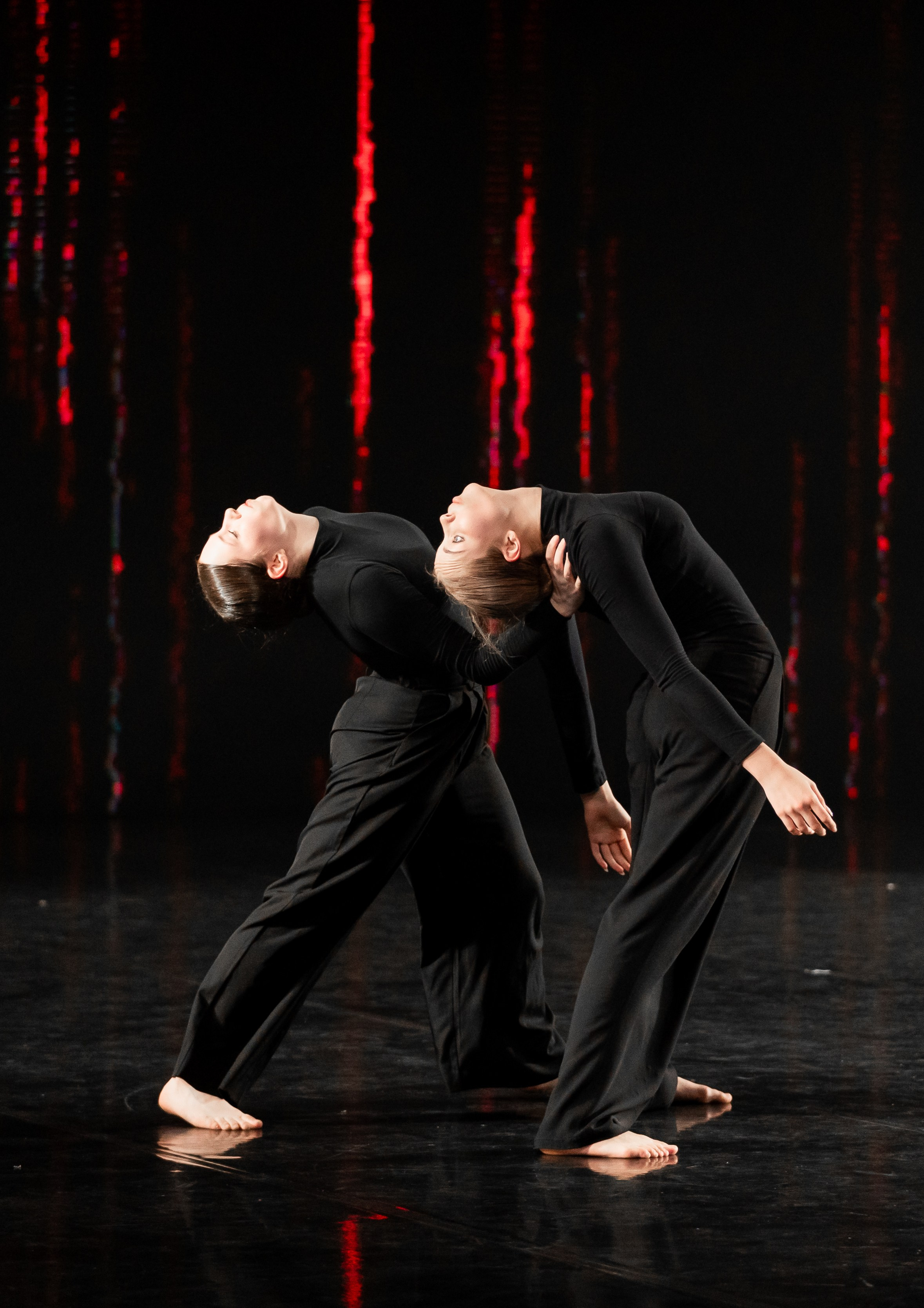 Академия танца Б. Эйфмана. Дуэт современного танца: две танцовщицы в чёрных костюмах выполняют сложную пластическую композицию на сцене. Профессиональная фотография танца. Автор: Евгений Мальцев (evrednix.ru).