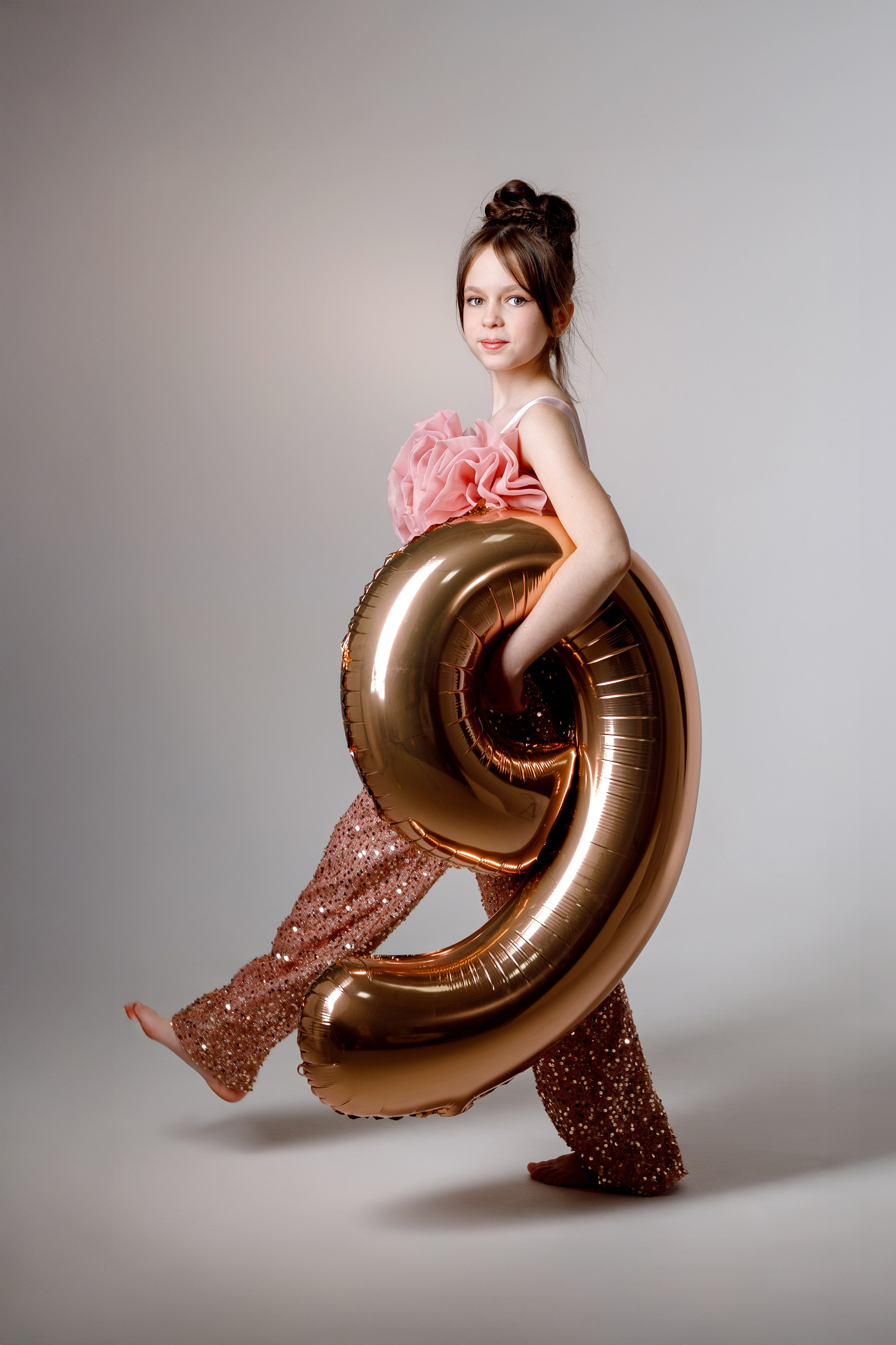 Девочка в брюках с пайетками позирует в фотостудии в Сочи с шаром в виде цифры 9 на детской фотосессии