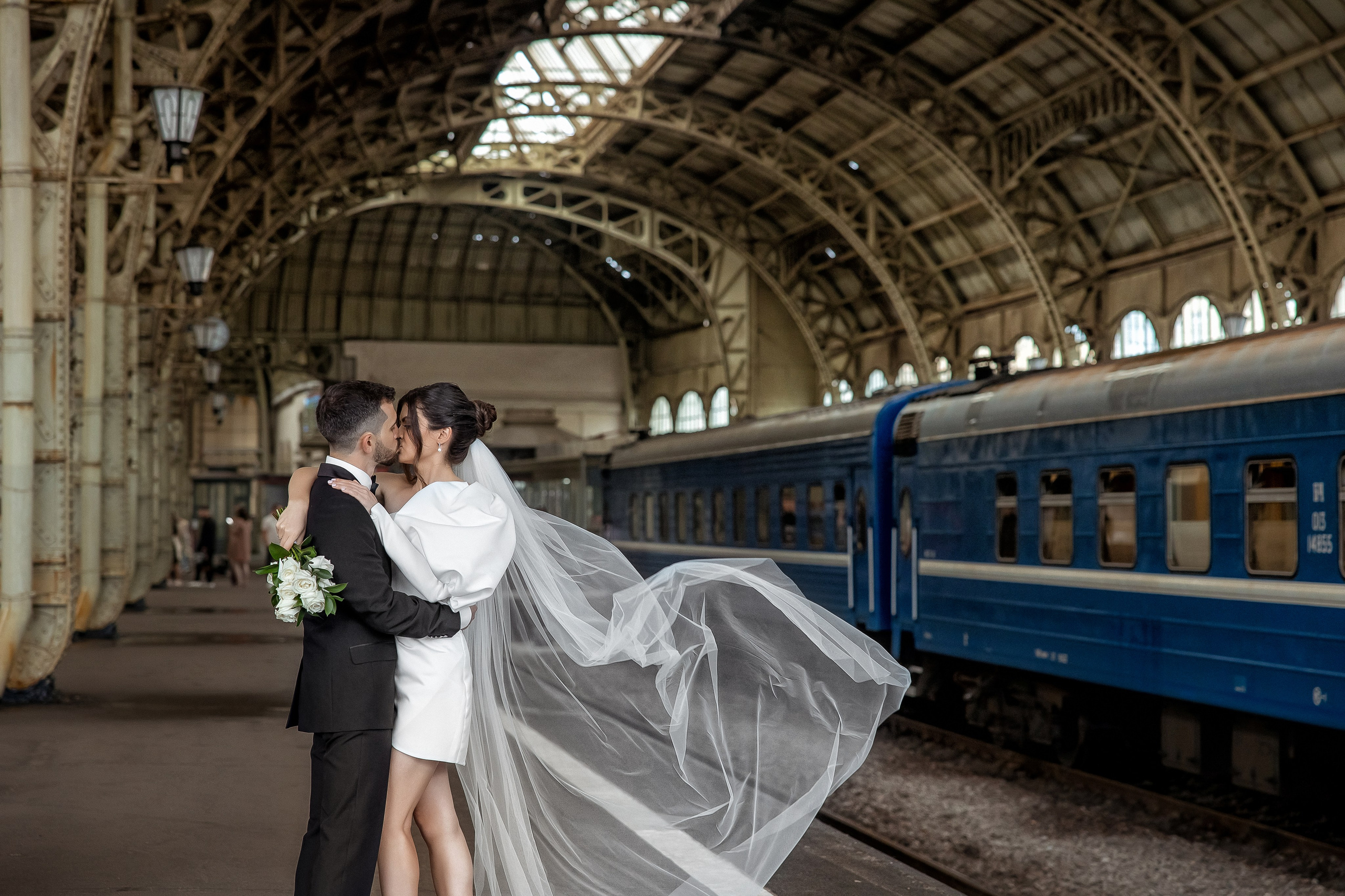 Жених и невеста обнимаются на перроне Витебского вокзала на фоне поезда