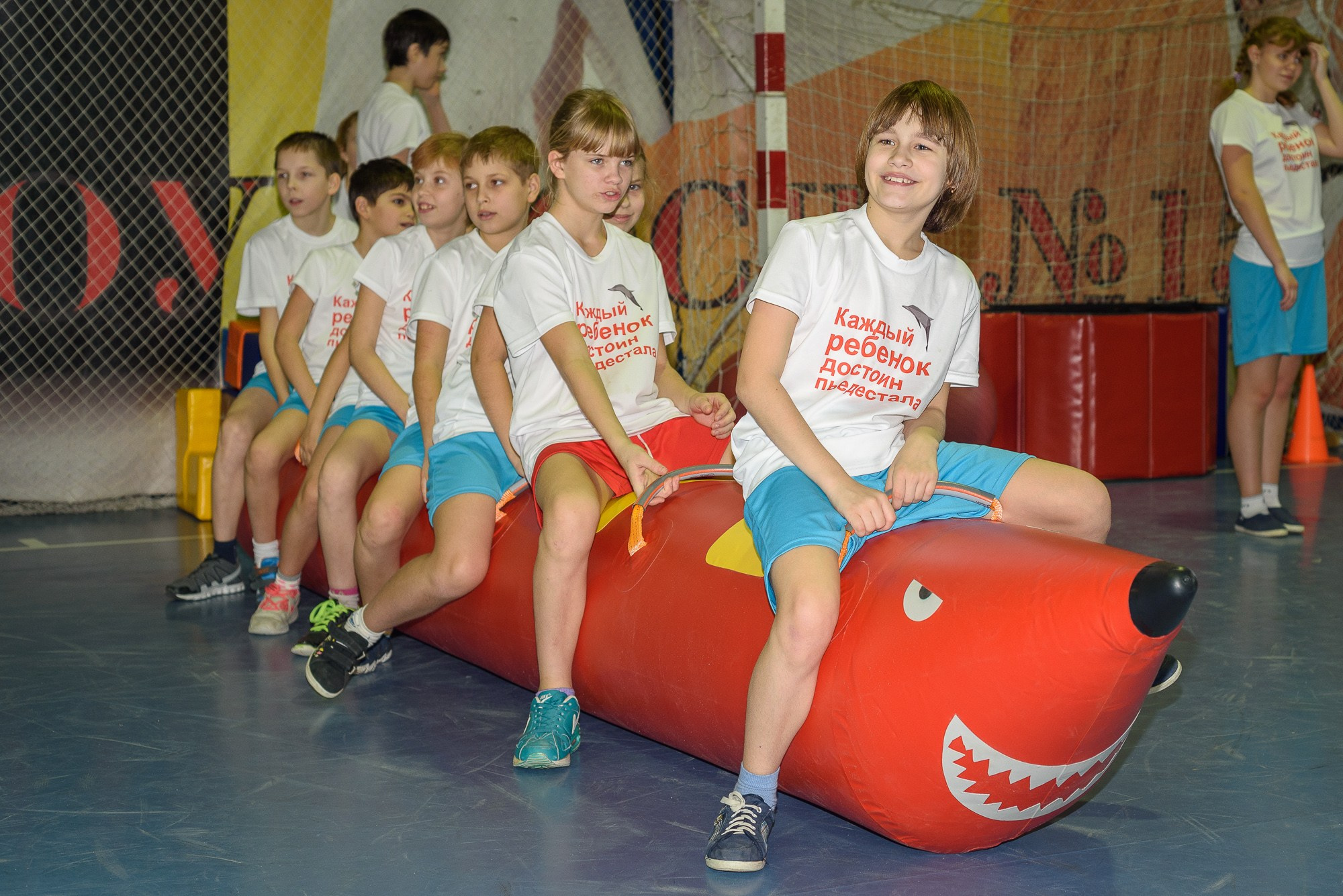 Участники соревнований смеются, сидя на надувном "банане"