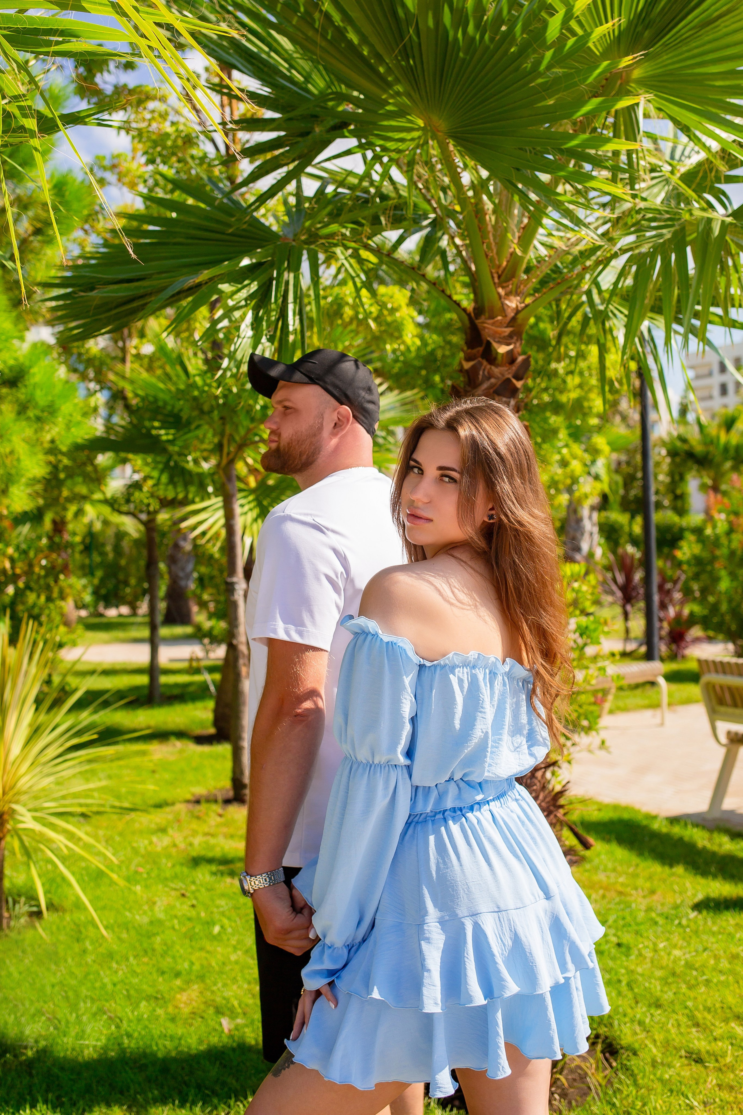 Влюбленная пара гуляет среди экзотических деревьев в Музыкальном саду Олимпийского парка.