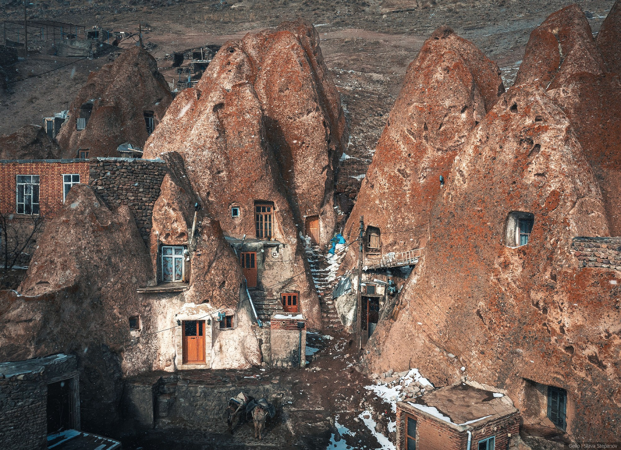 The unique rock village of Kandovan in winter. Residential homes carved into cone-shaped rocks against a backdrop of light snow. Photo by Gelio.