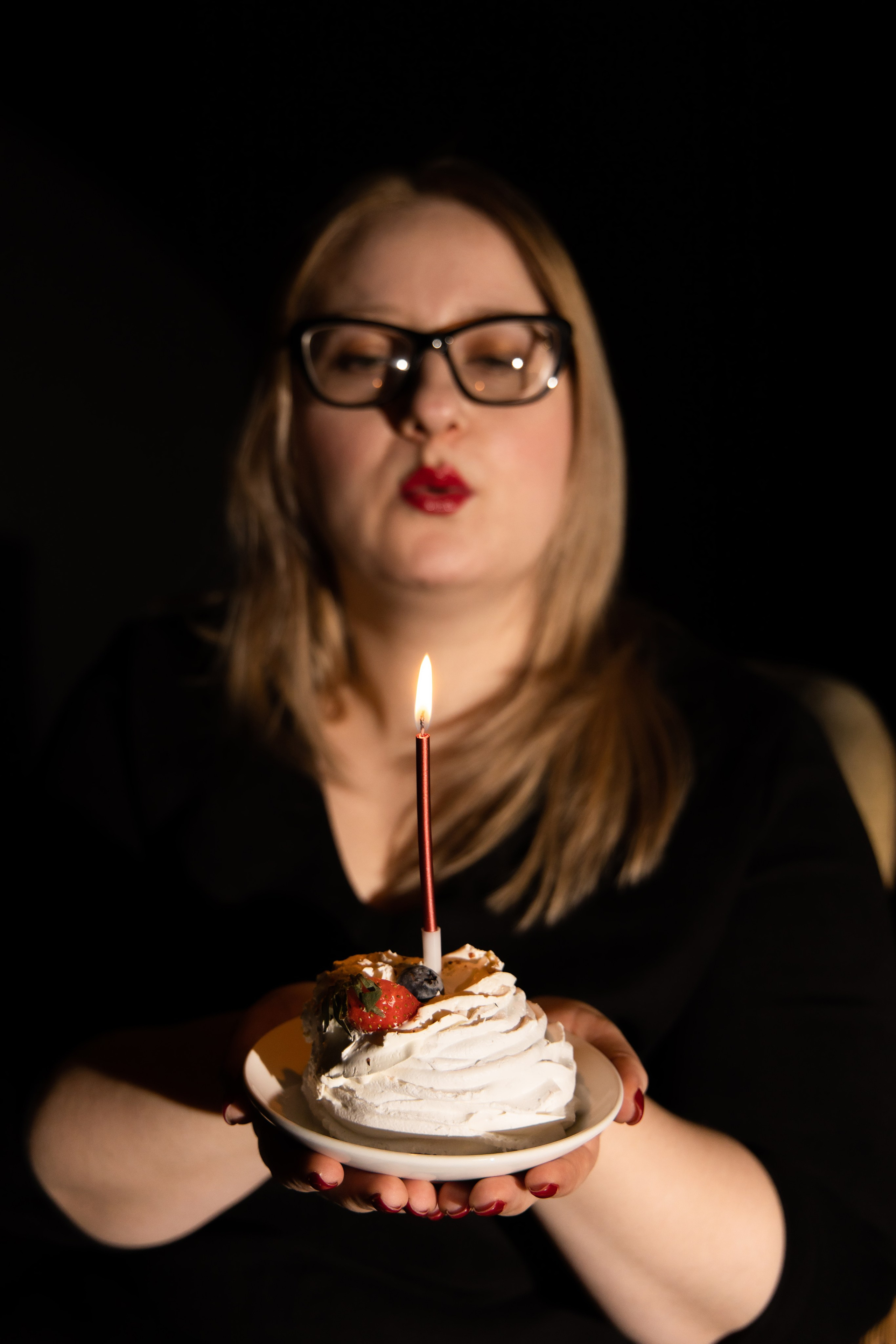Девушка стоит и держит перед собой пирожное со свечкой. Студийная съёмка Астрахань.