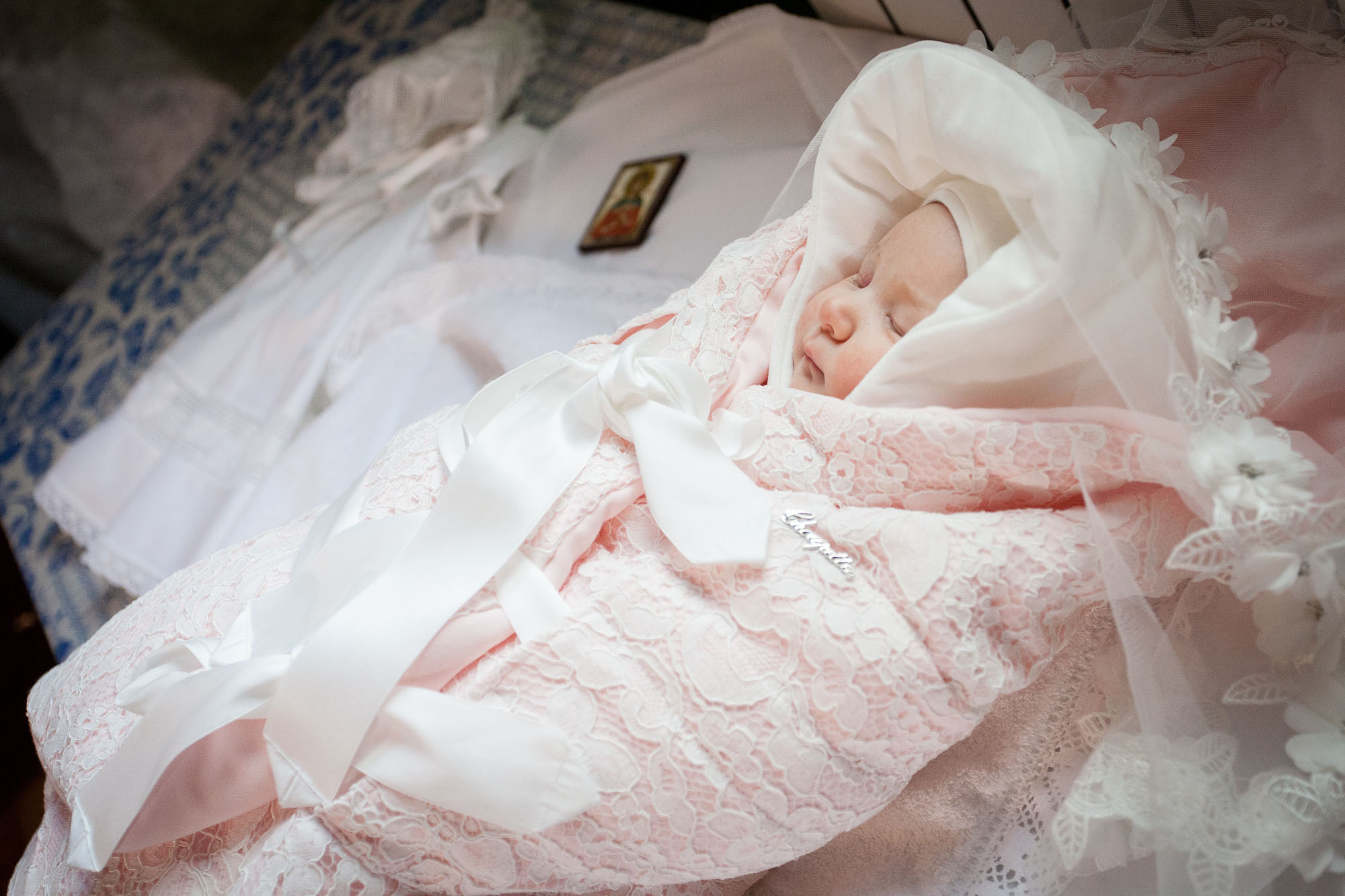 Младенец в розовом одеяле лежит на пеленальном столе.