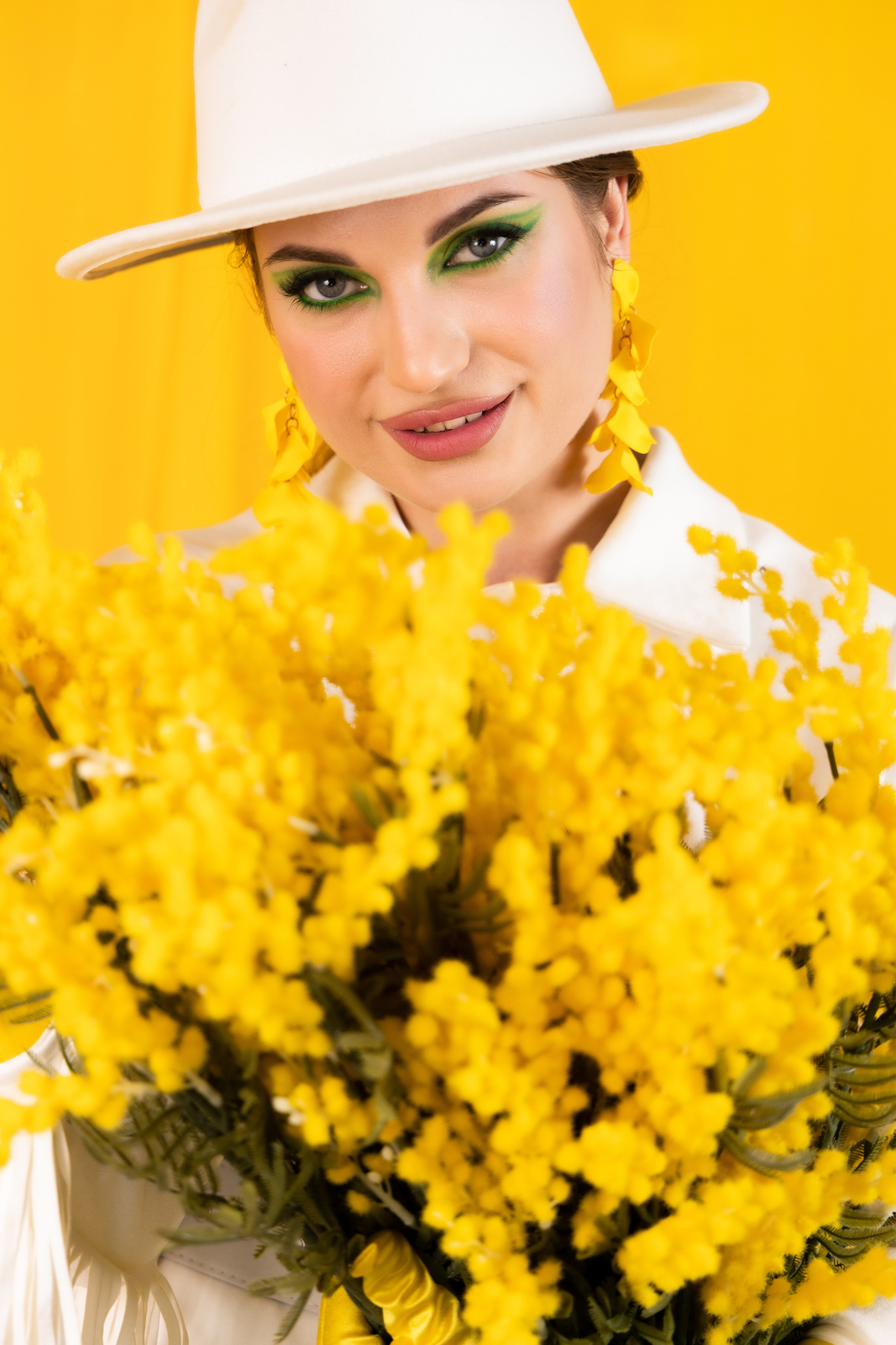 Студия "Хамелеон", весенний образ, белый костюм и жёлтые перчатки. В руках у девушки букет желтой мимозы. Студийная съёмка Астрахань.