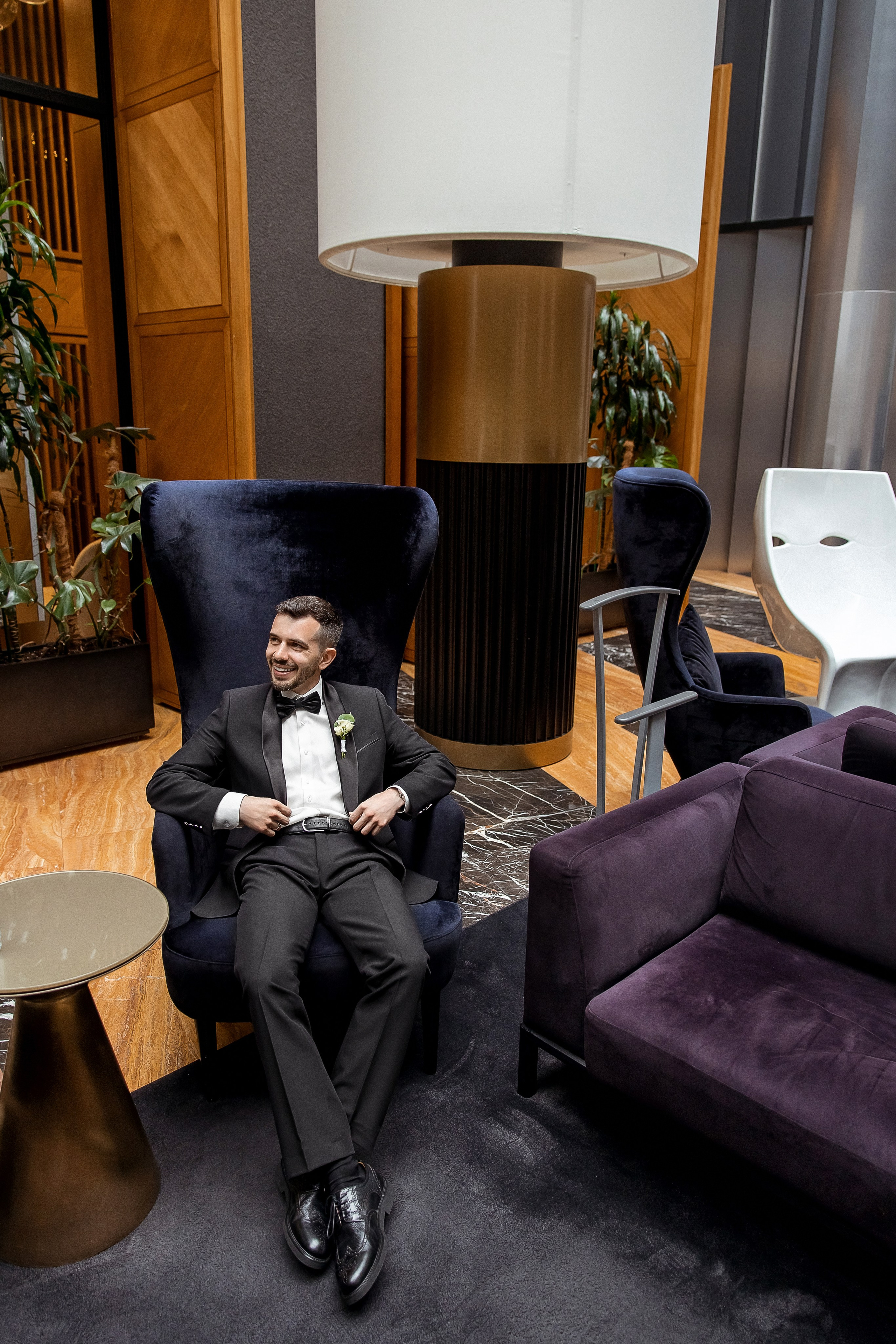 Стильный портрет жениха, сидящего в кресле в лобби отеля Гамма в Санкт-Петербурге