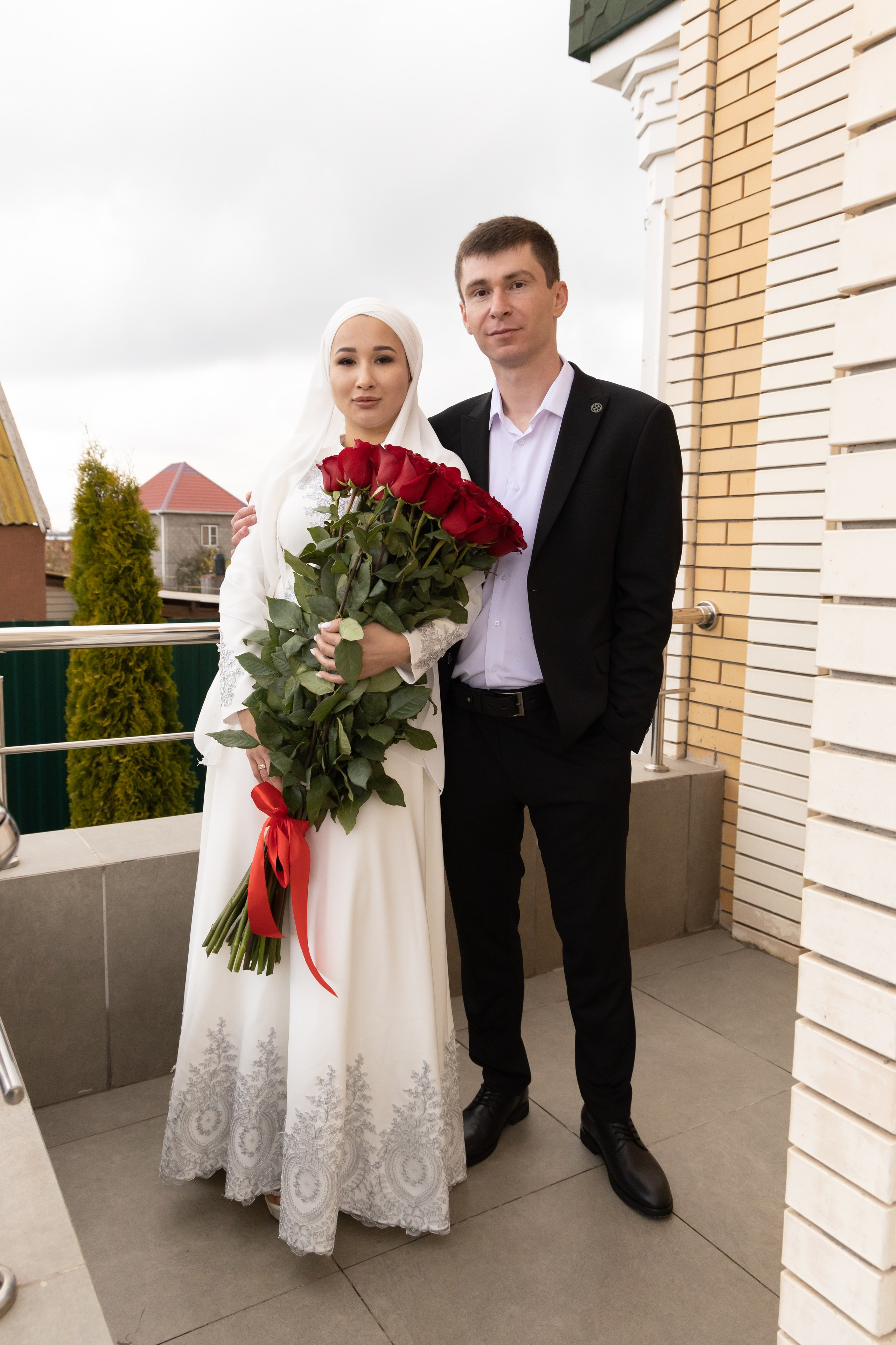 Молодожены в полный рост, у девушки большой букет красных роз. Свадебная фотосессия Астрахань.