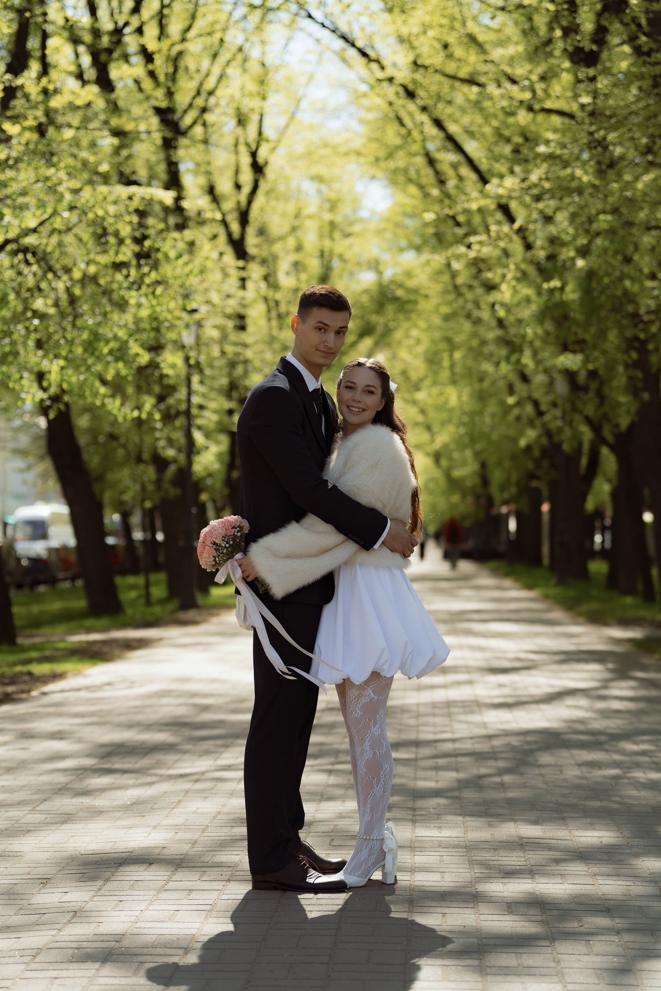 Объятия жениха и невесты в парке, свадебная фотосессия среди деревьев