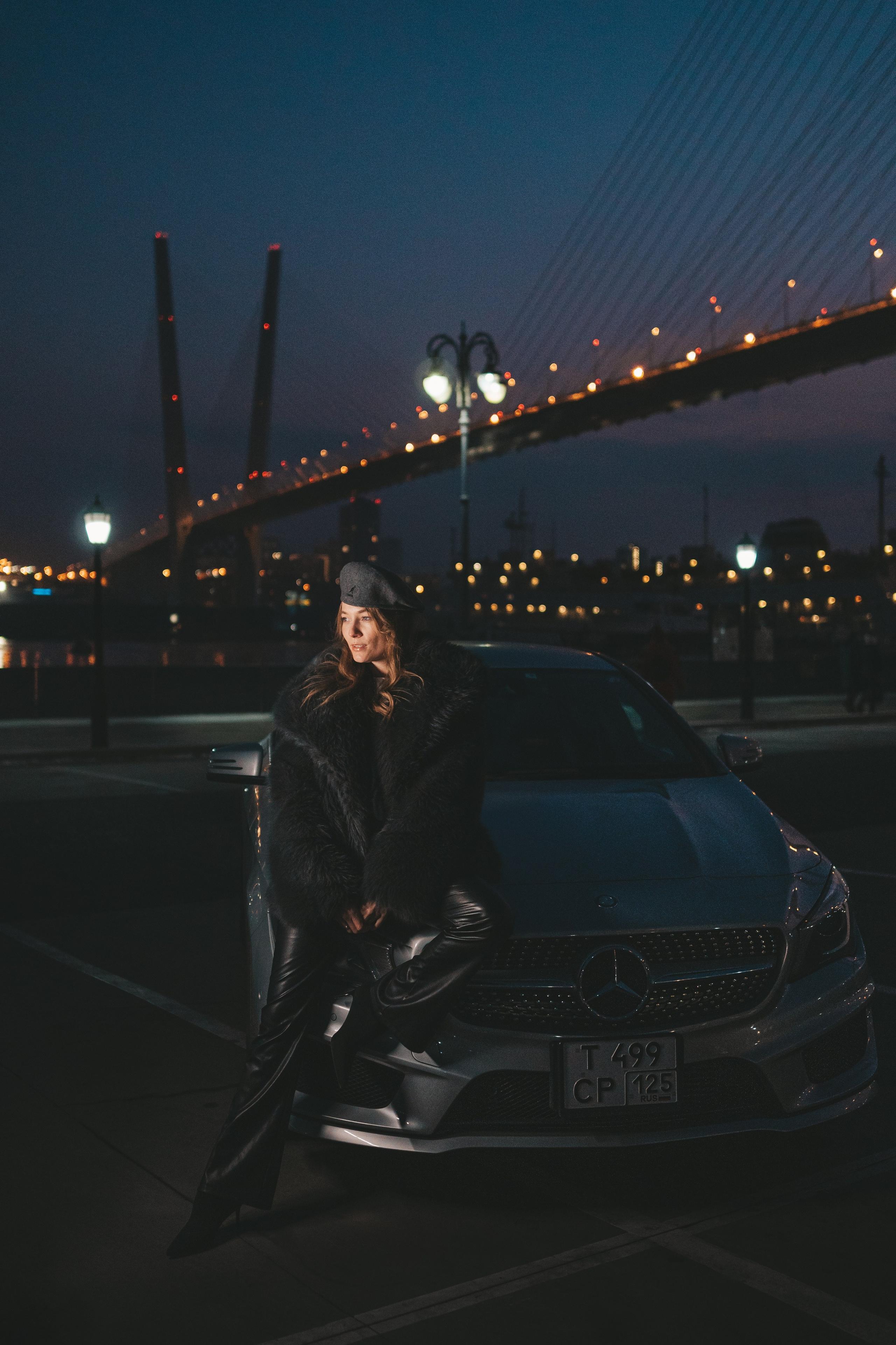 девушка прислонилась к своей машине мерседес,  на фоне мост
