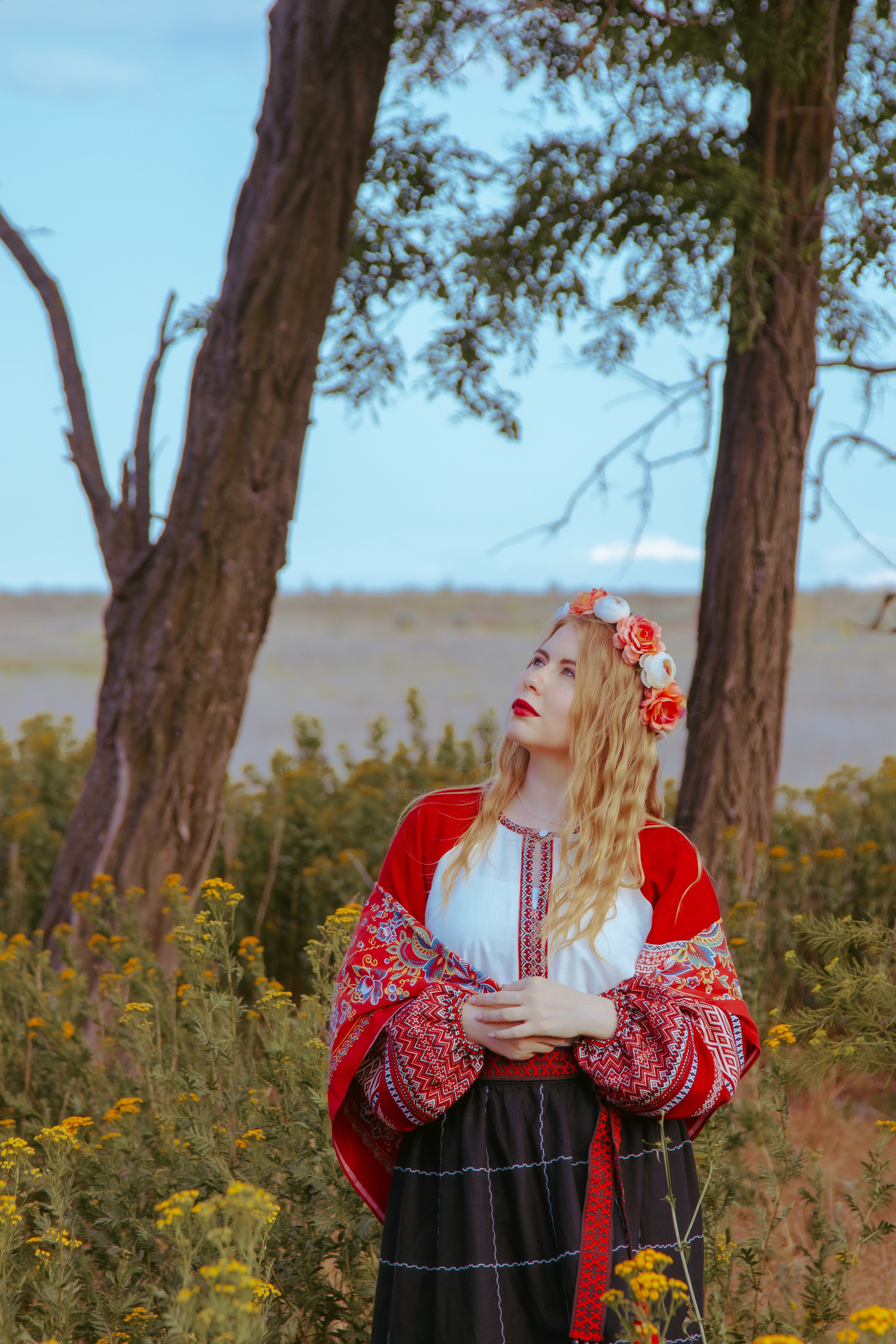 Портрет славянской девушки в жёлтом поле на фоне деревьев