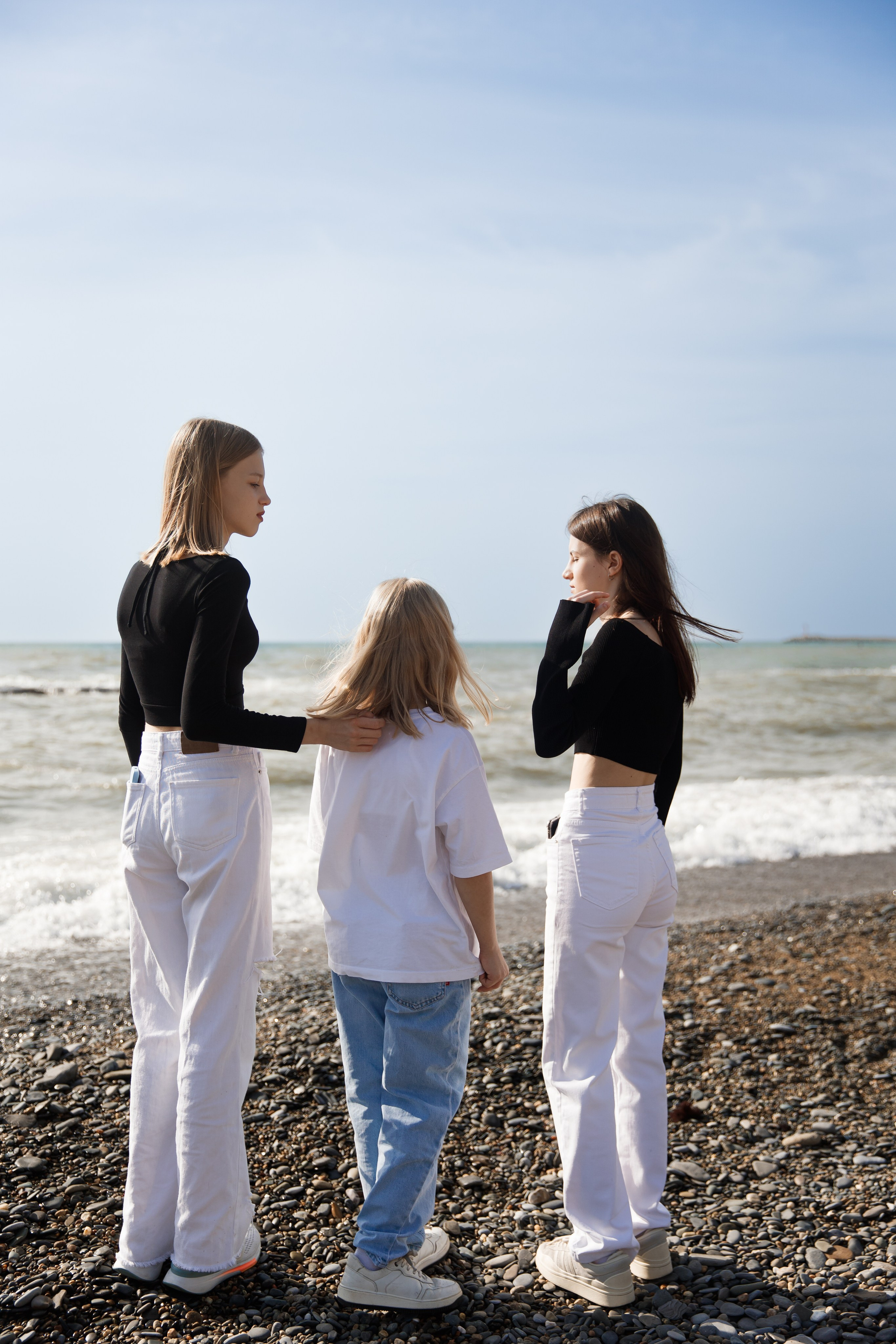 три девочки стоят на фоне штормового моря и Разговаривают друг с другом