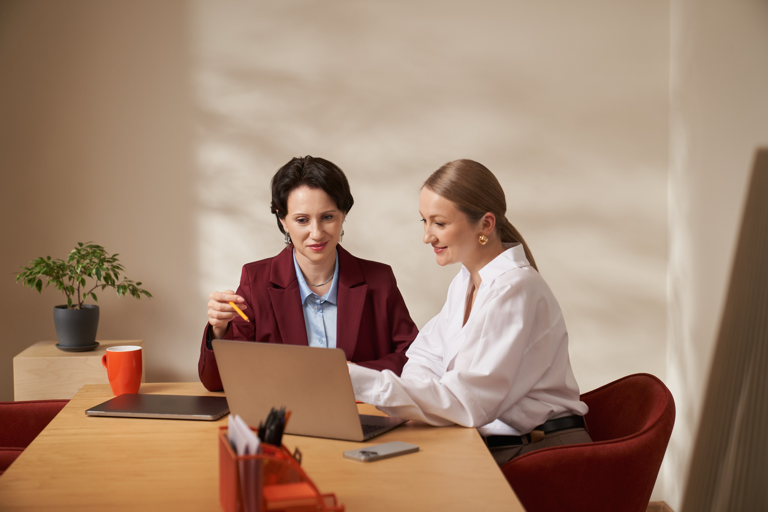 Мужчина в зелёном свитере разговаривает по телефону в офисе, держит папку с документами