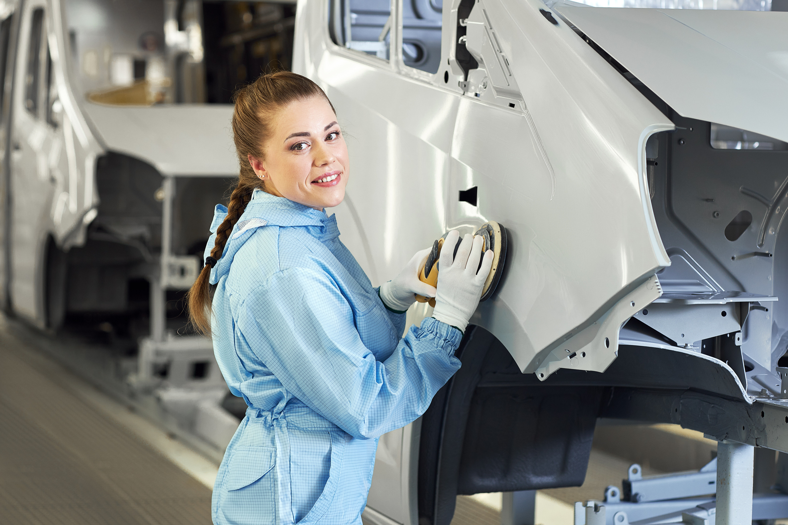 Сотрудница завода полирует поверхность нового автомобиля.