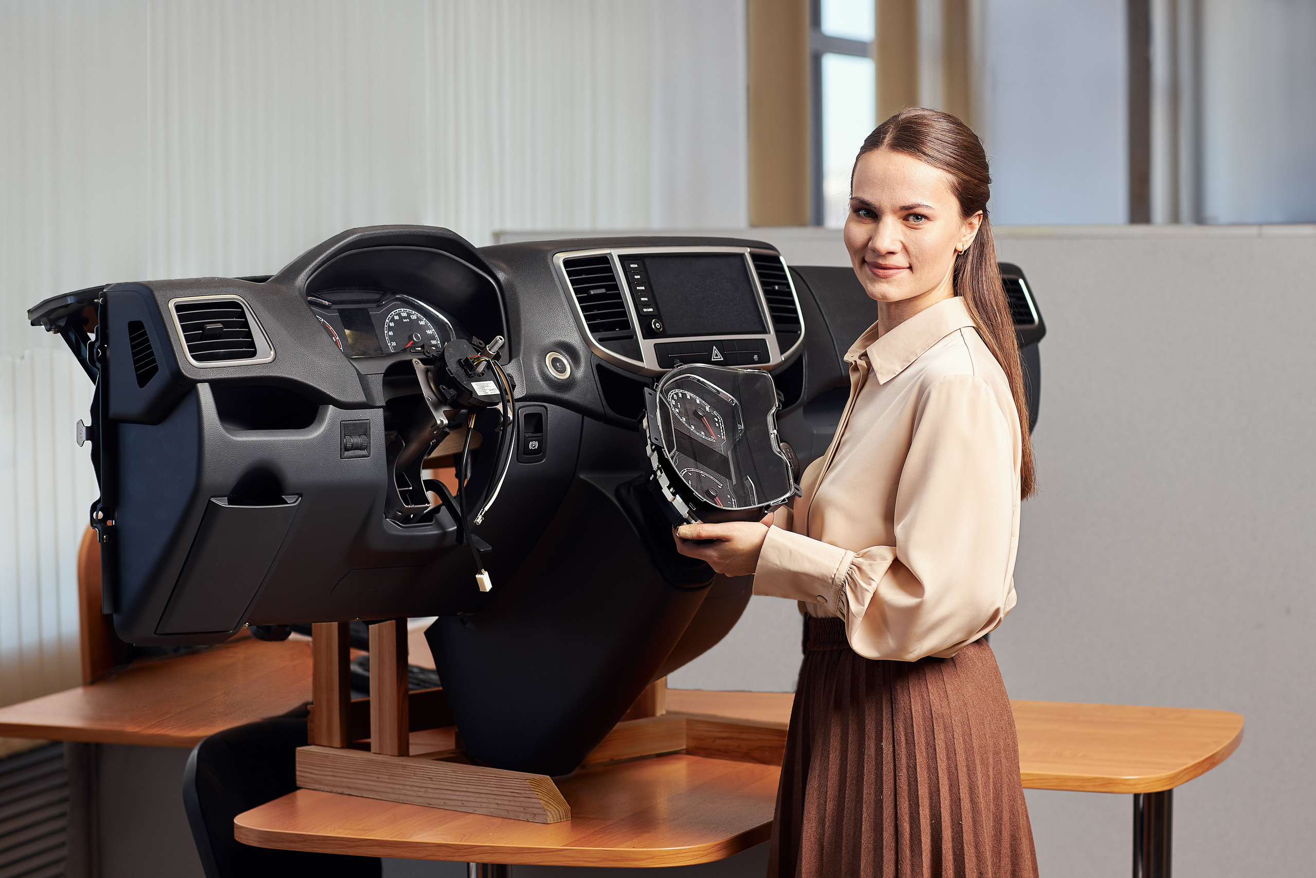 Девушка демонстрирует стенд для тестов. Участвует в фотосъёмке на предприятии.