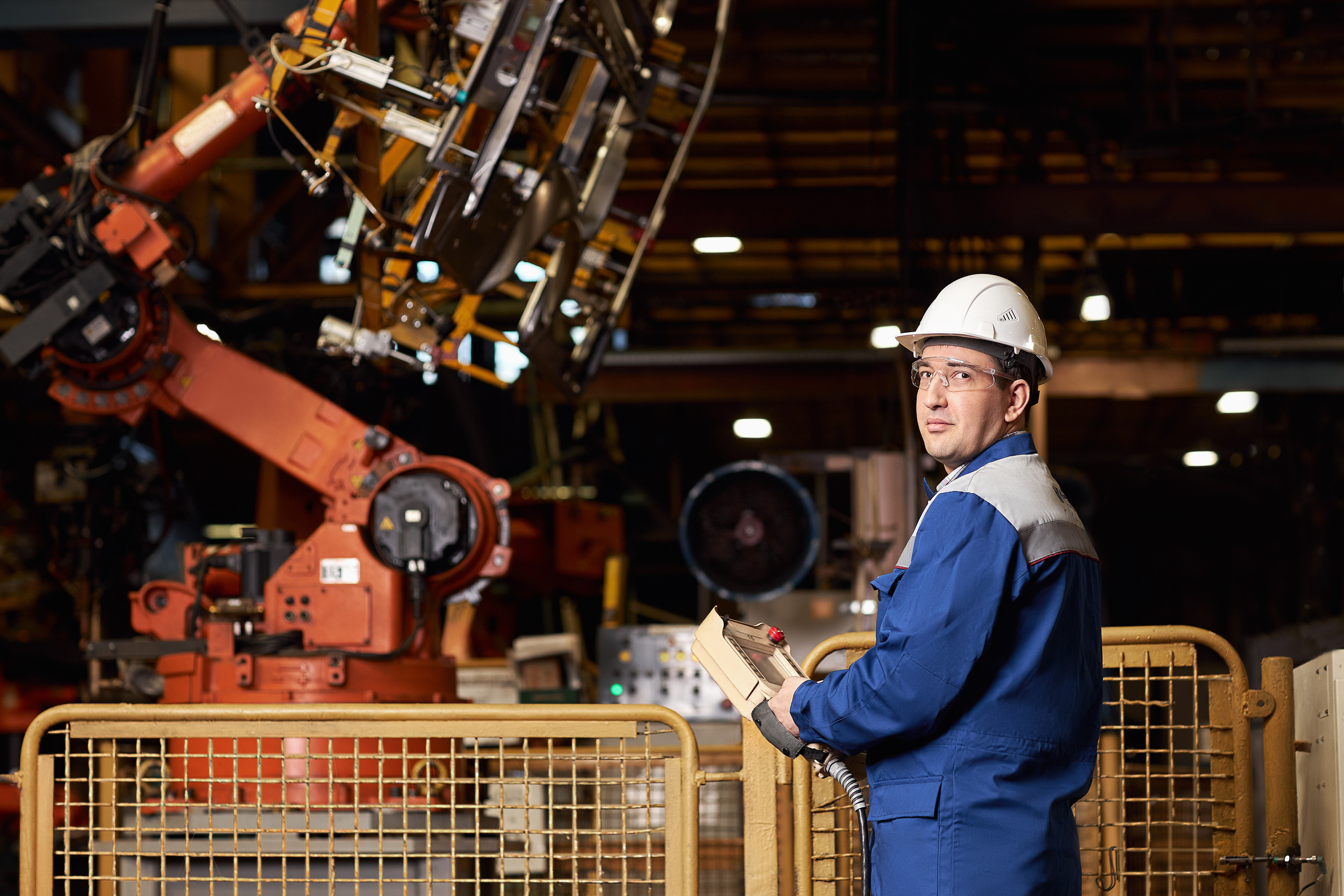 Инженер руководит работой робота на заводе.