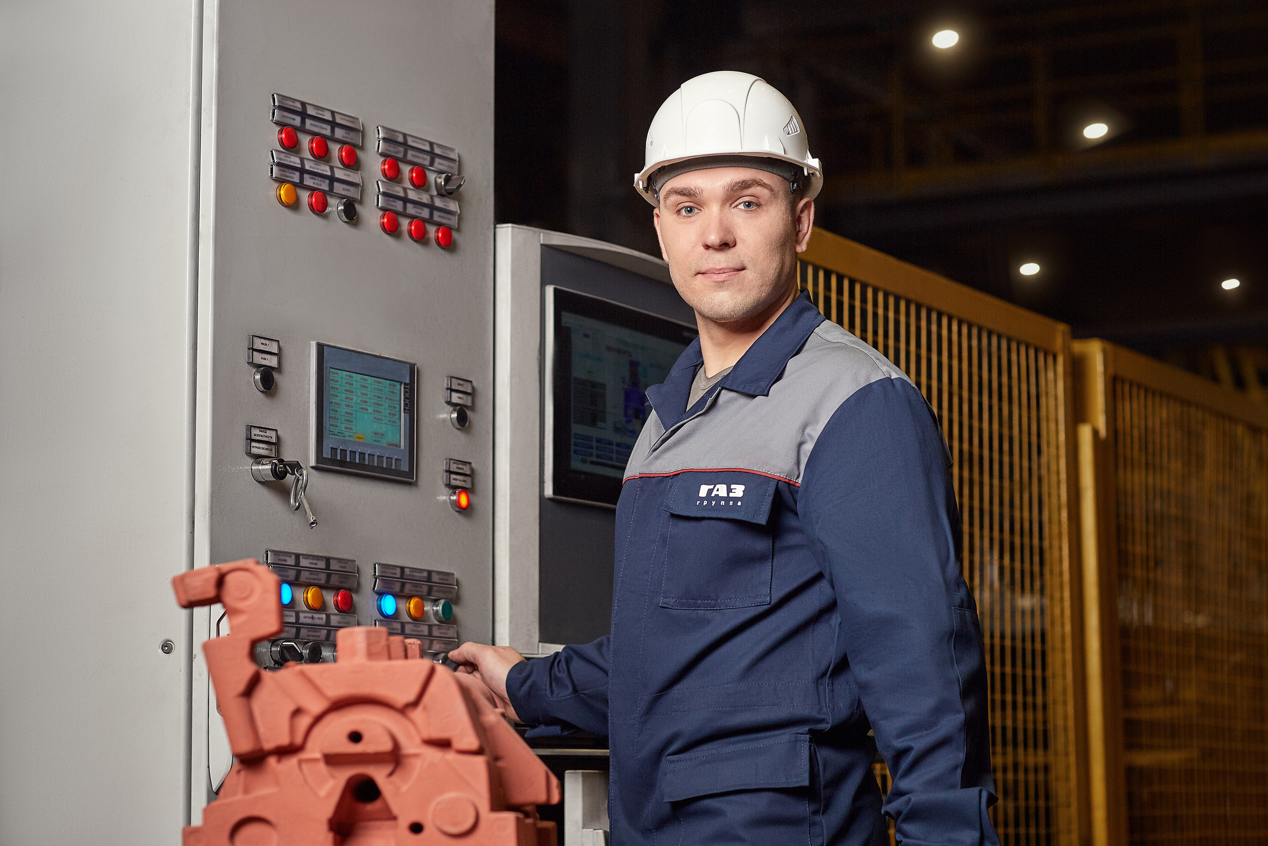 Рабочий стоит около пульта управления. Фотосъёмка на предприятии.