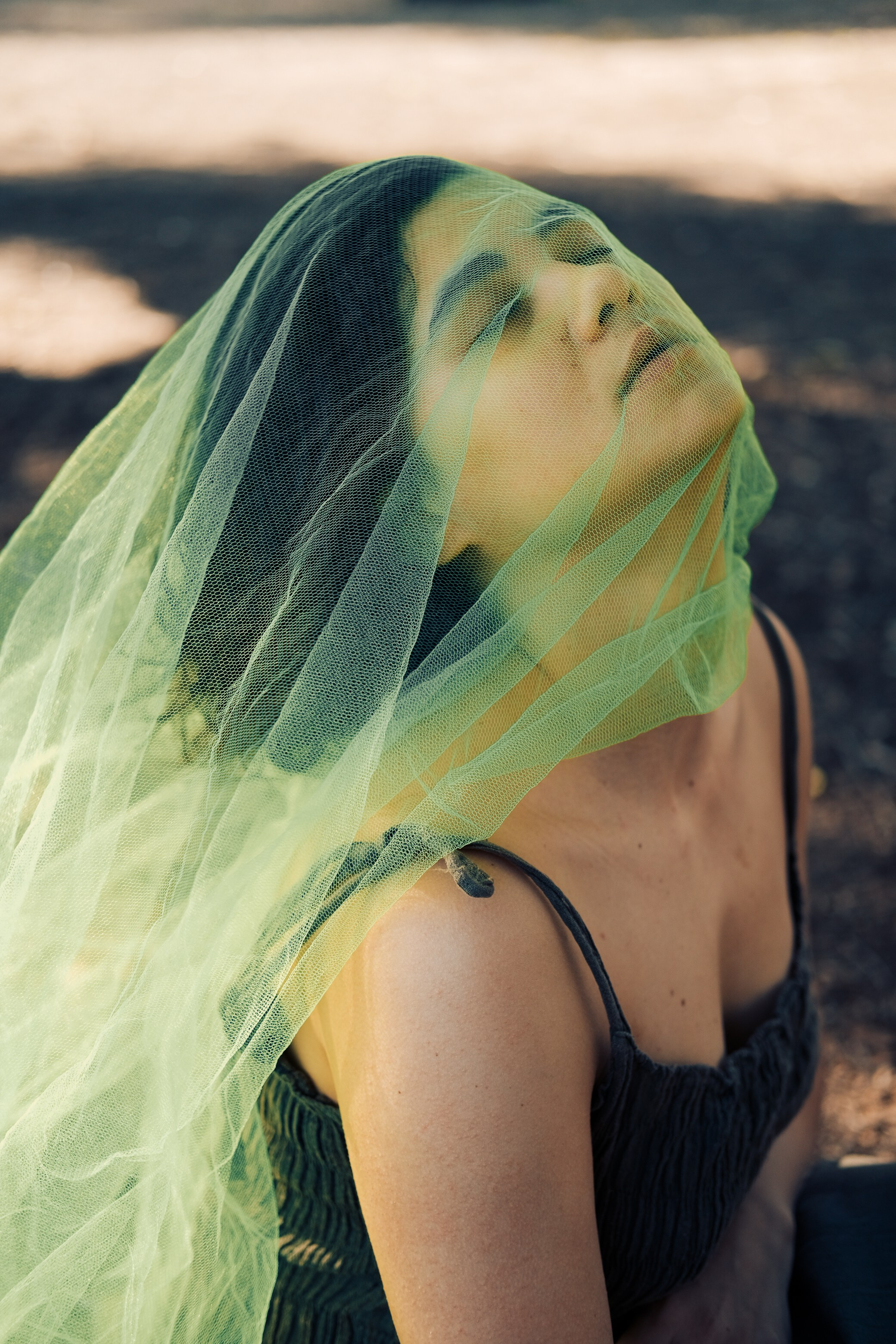 Девушка с зеленой тканью на лице, подняла голову вверх