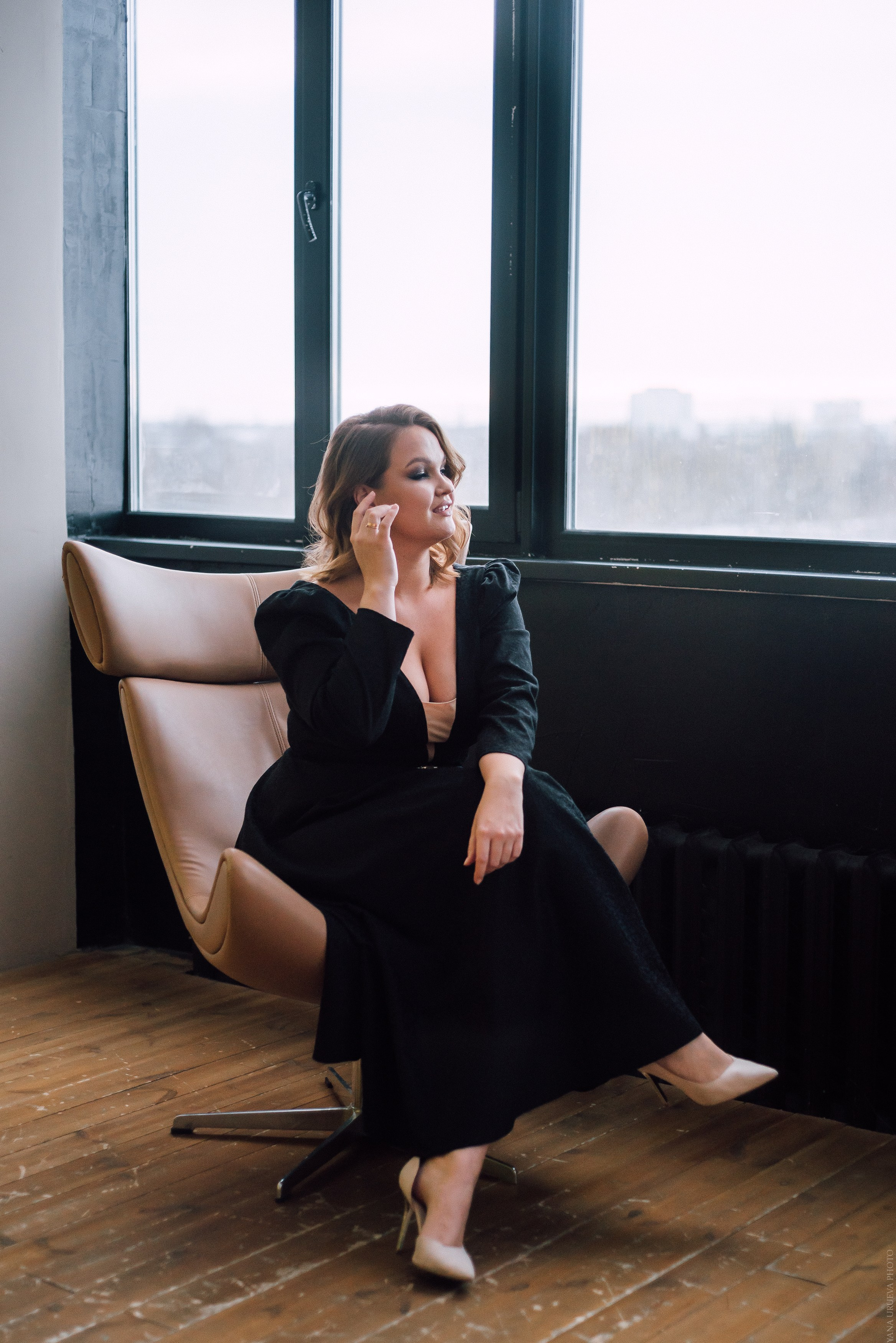 Двушка в черном платье сидит в кресле