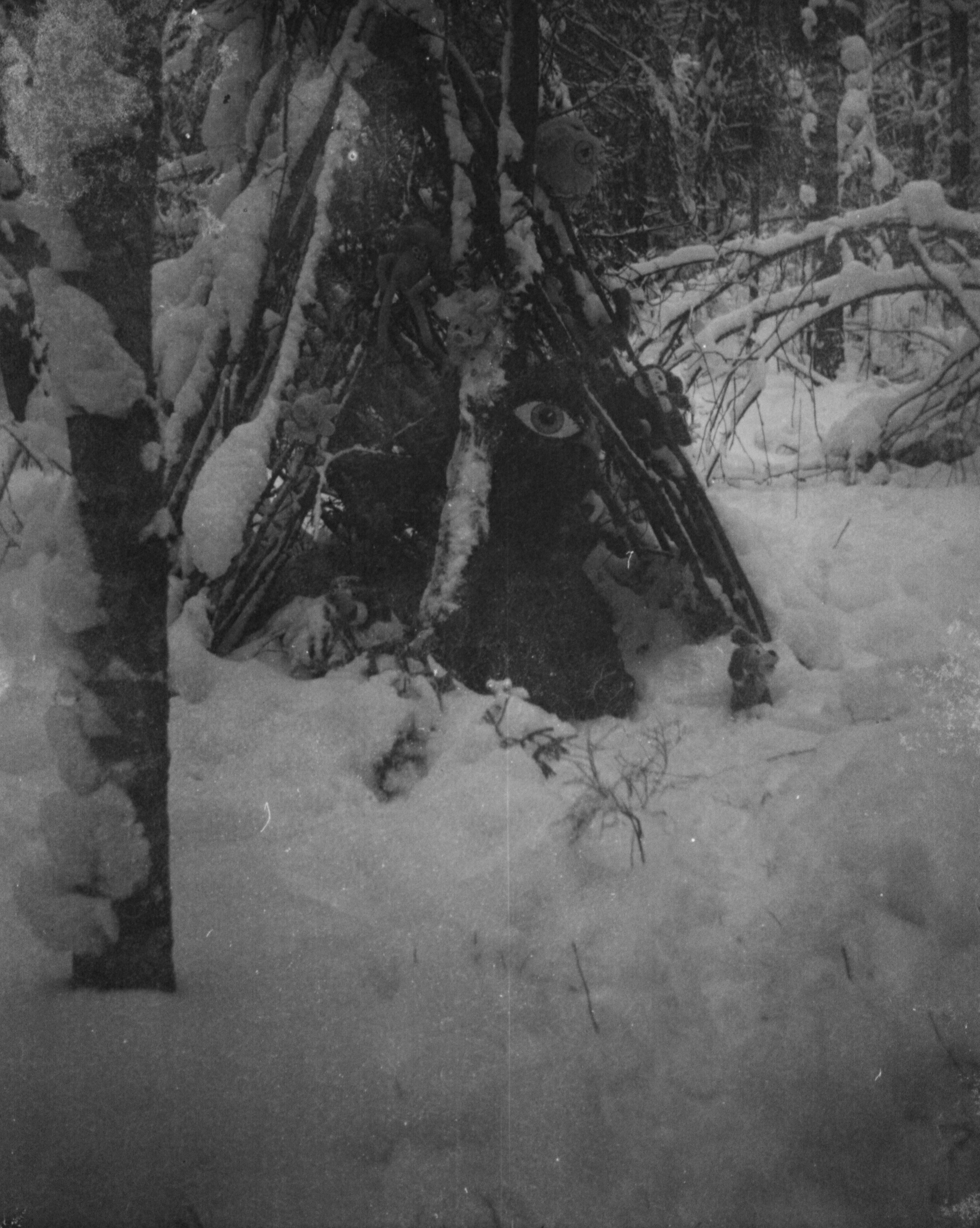 Плёночная фотография монстра в шалаше в зимнем лесу.