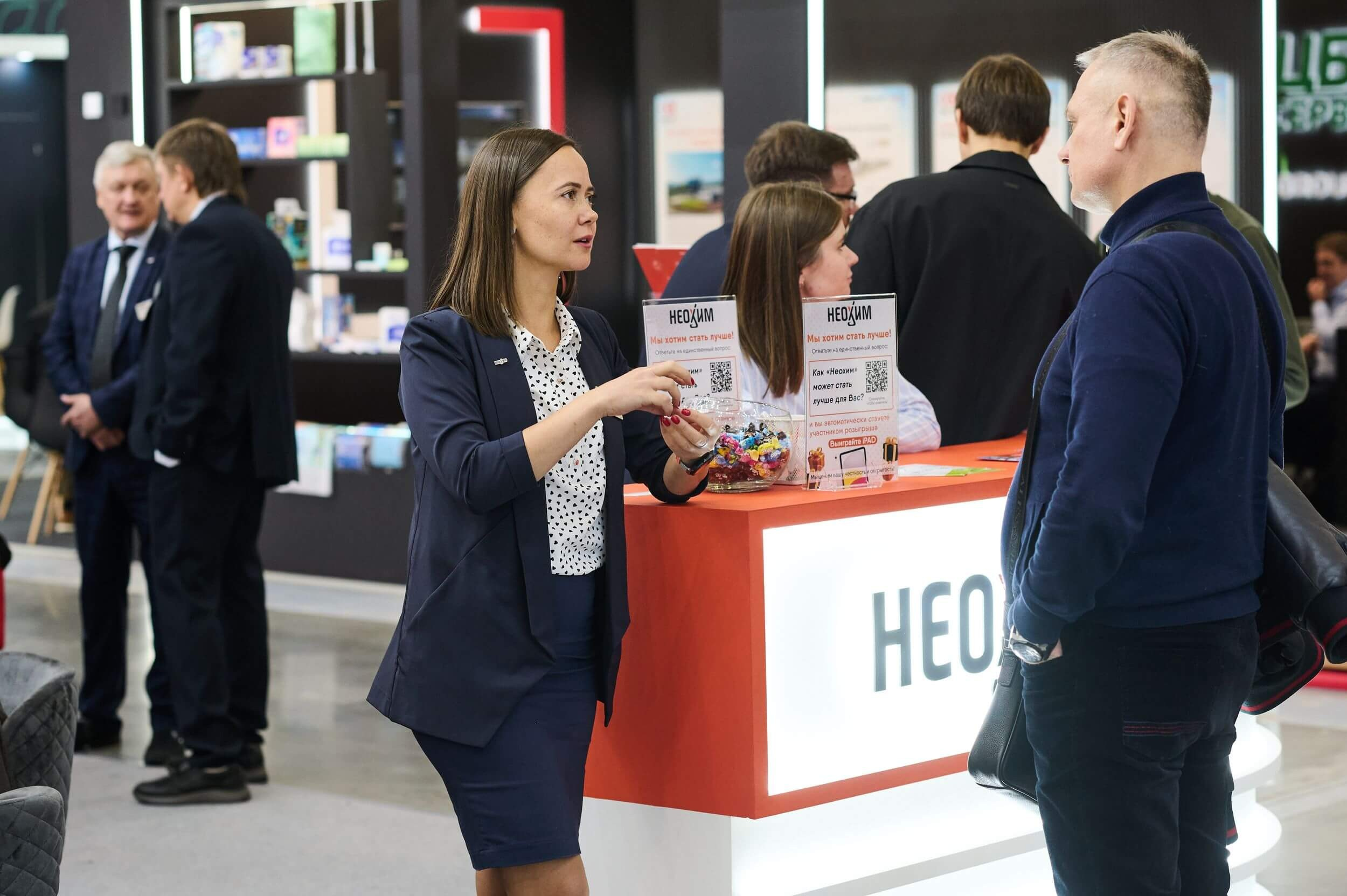 29. Стенд компании Neohim: сотрудница объясняет продукцию посетителю.
