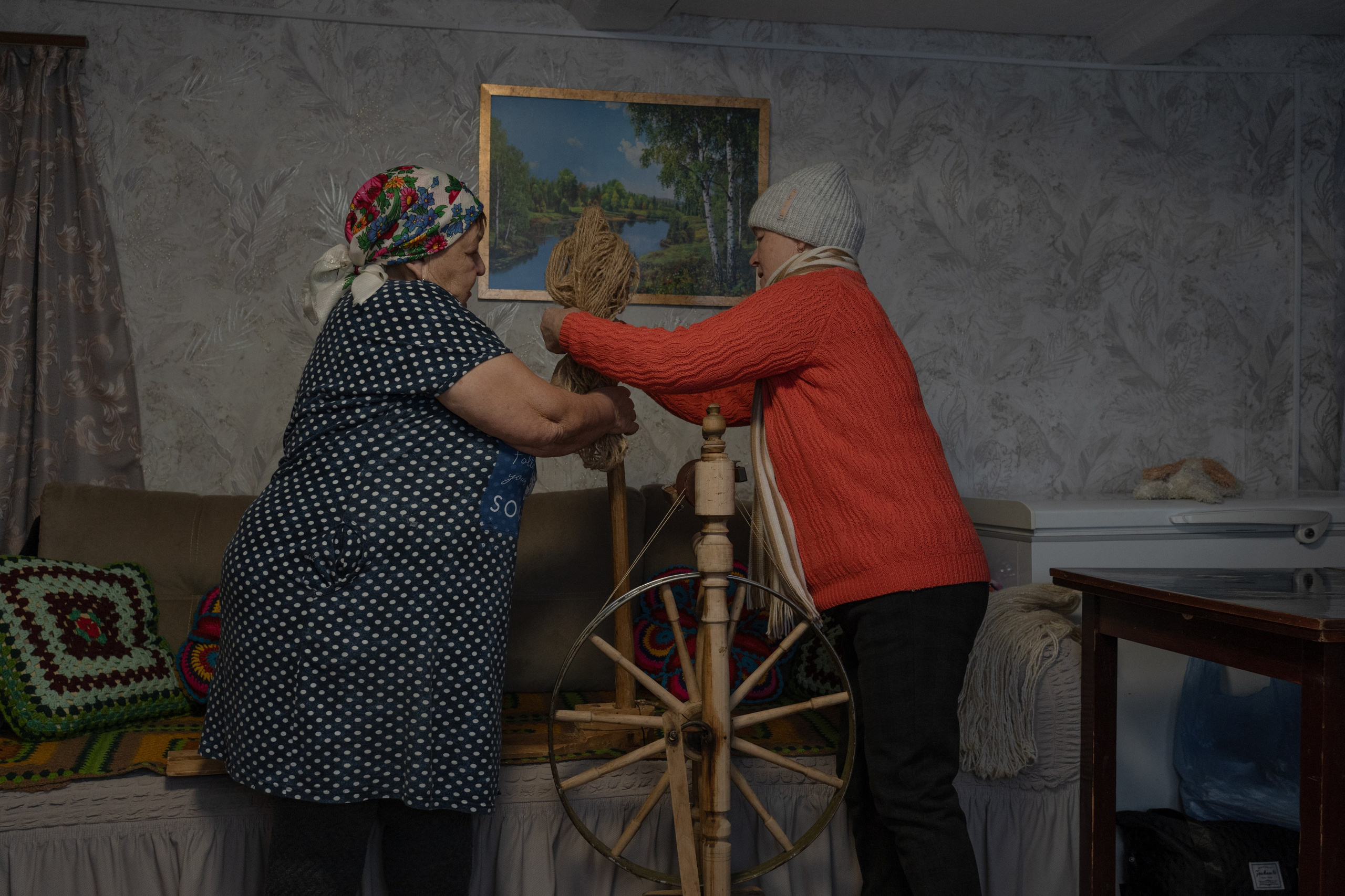 Женщины крепят шерстяную пряжу на традиционную чувашскую прялку. Прялка досталась Елене Мишуткиной (слева на фото) от матери и до сих пор используется в быту. Поселок Сирмабусь (находится в составе сельского поселения Староганькино), Самарская область, декабрь 2023 год.