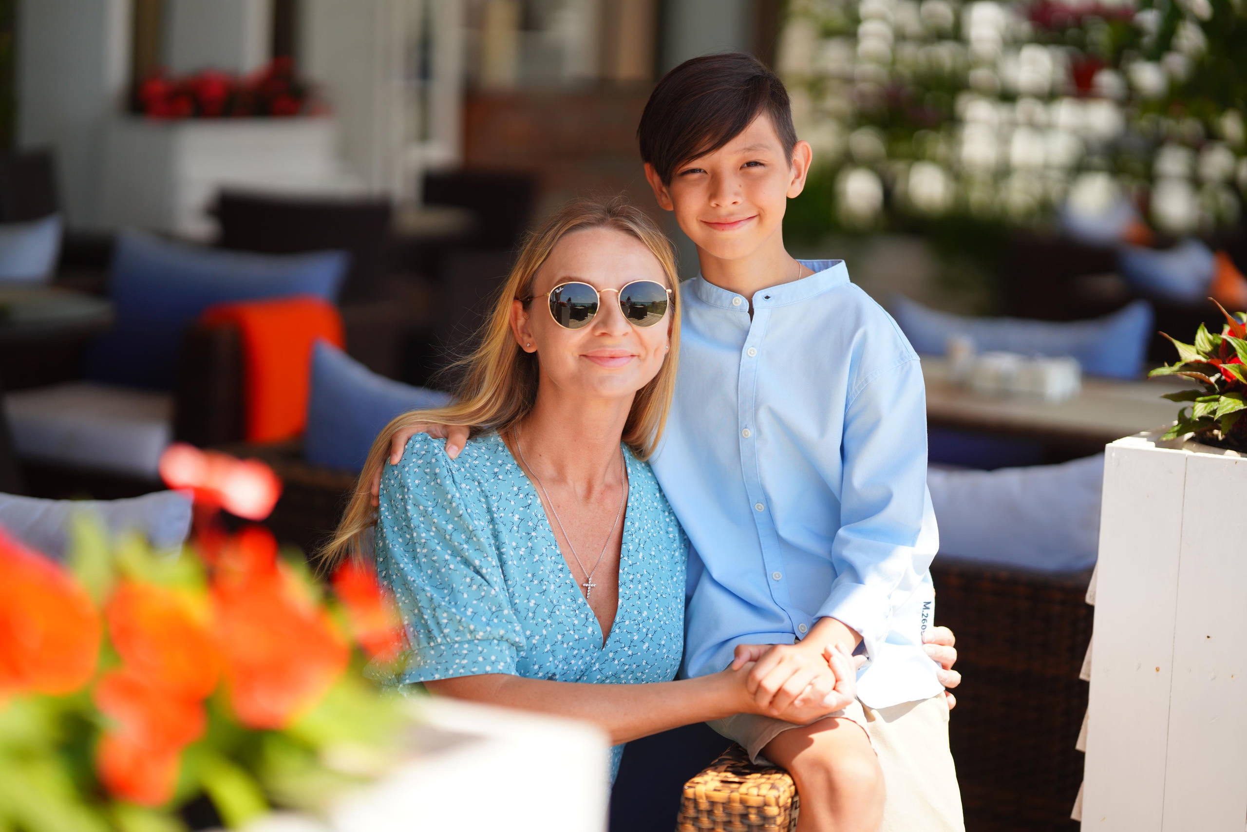 Мама обнимает сына сидя на кресле в кафе, они одеты в голубое