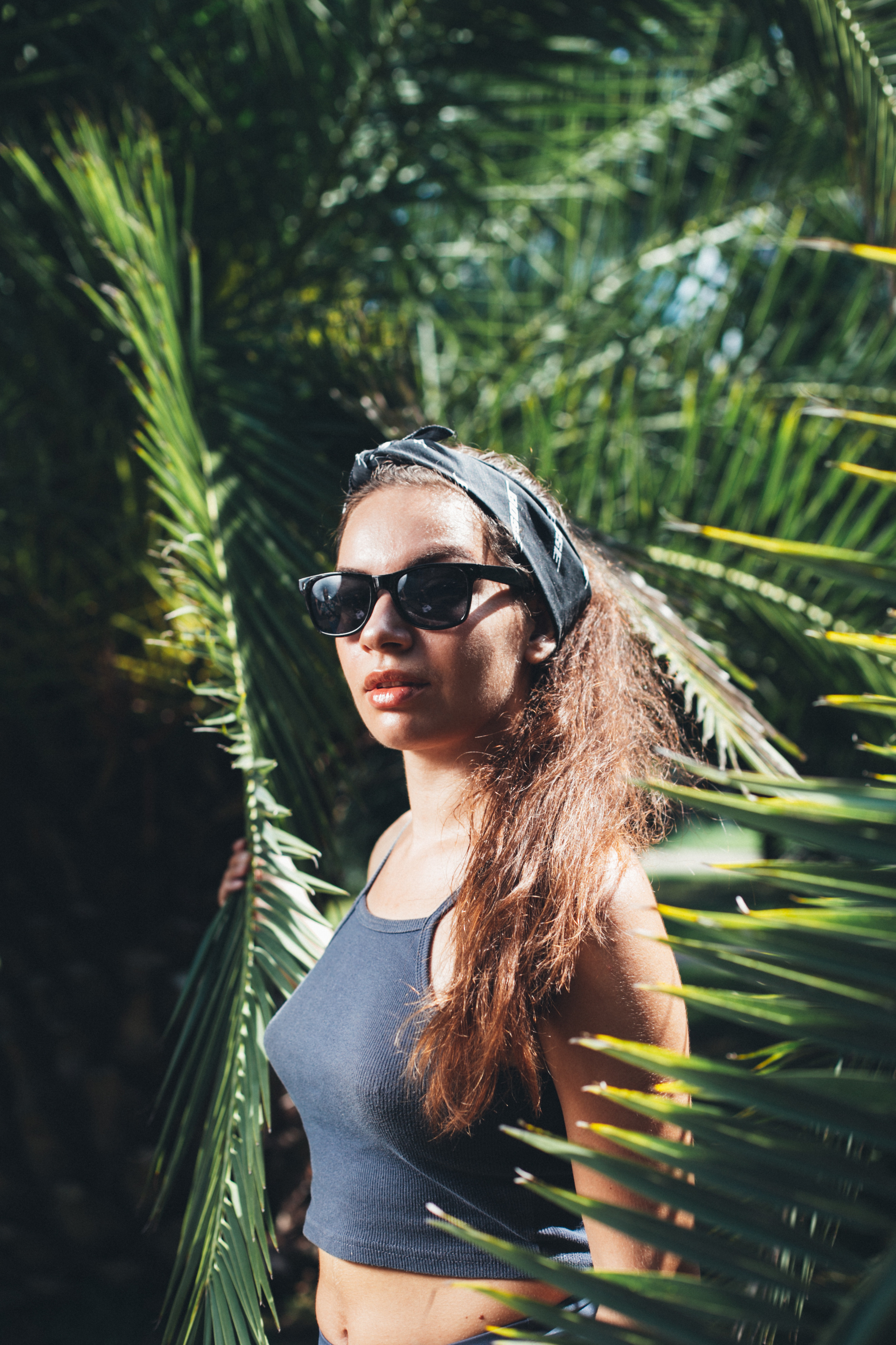 Девушка в очках в Серой майке и бандане позирует на фоне парень