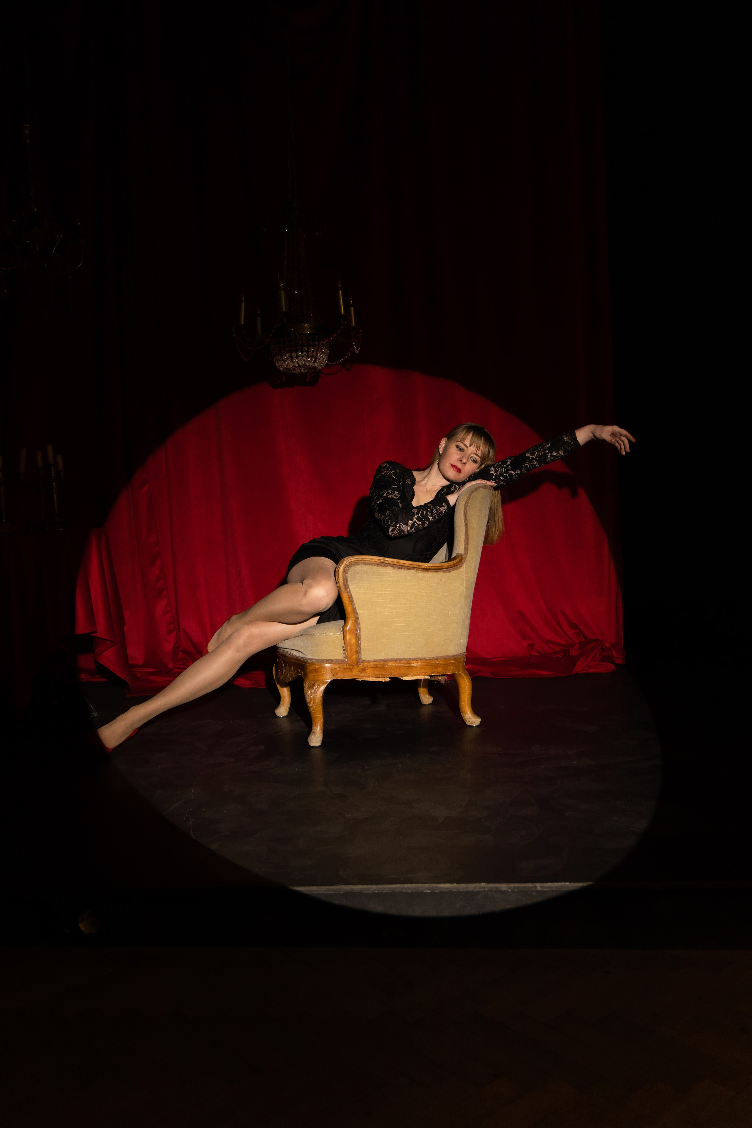 Девушка полулежит в кресле. Фотосессия на красном фоне. Студийная съёмка Астрахань.