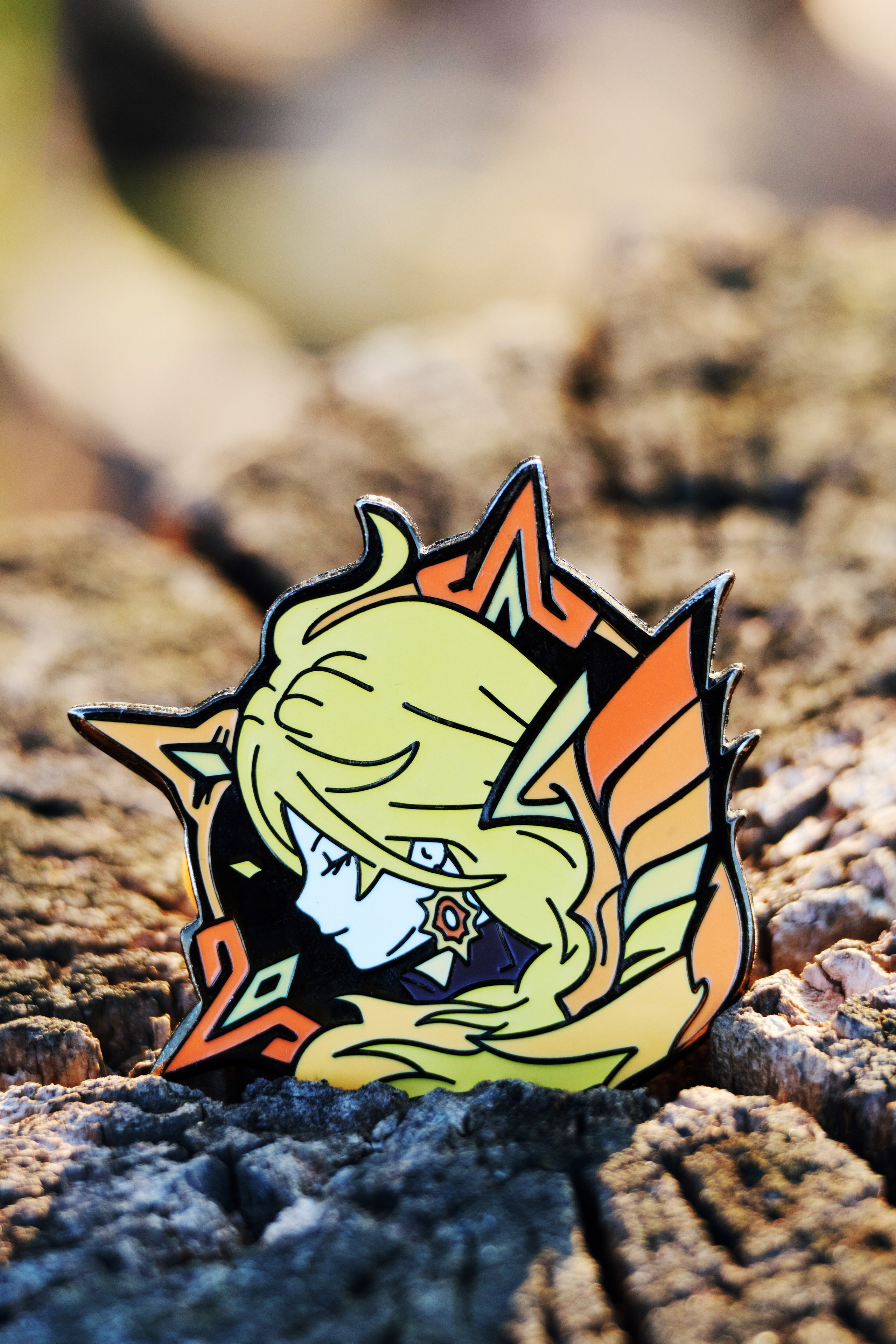 Мавуика из Genshin Impact - металлический пин крупным планом на фоне деревянного пня