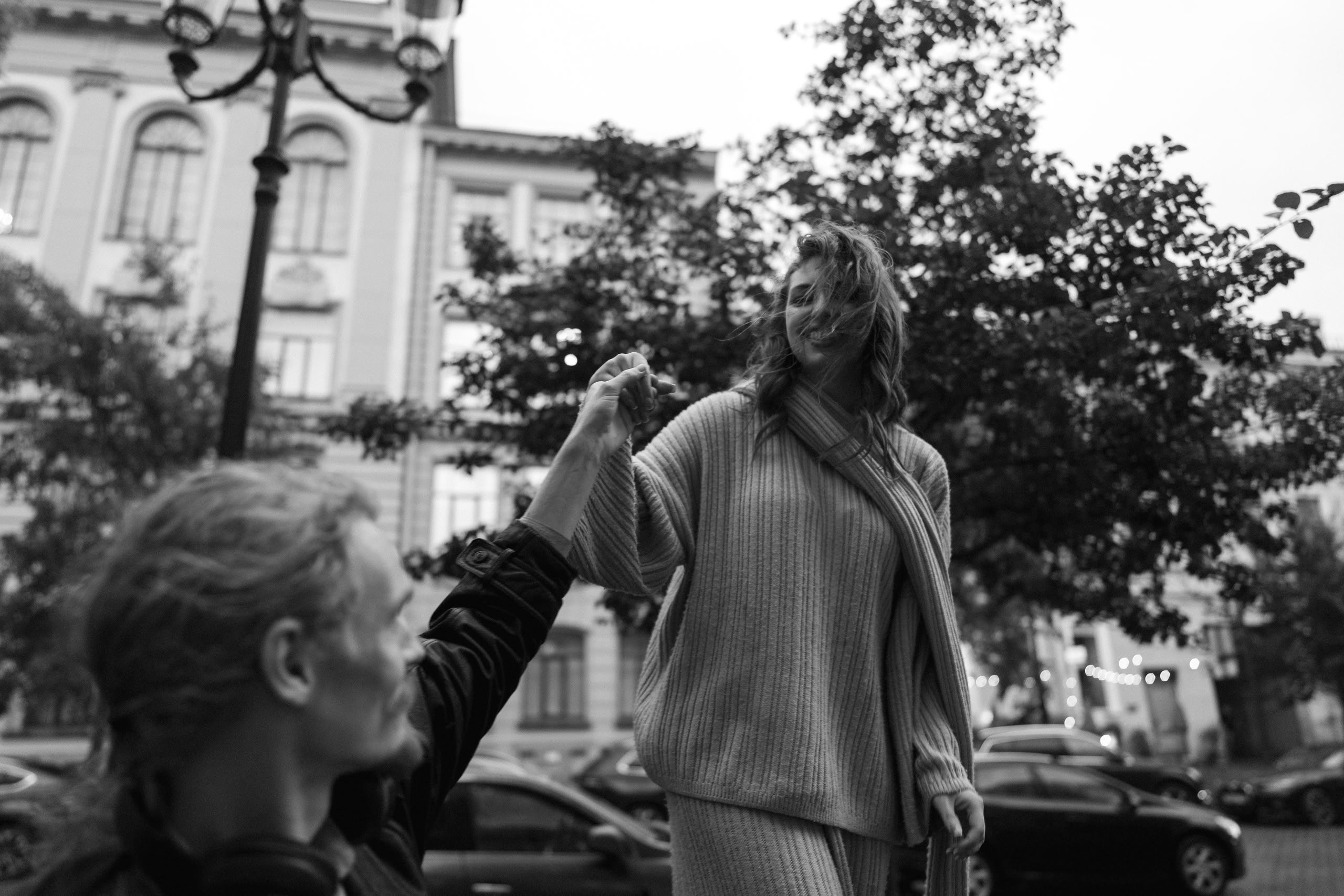 Чёрно-белый кадр: пара в уличной сцене с деревьями